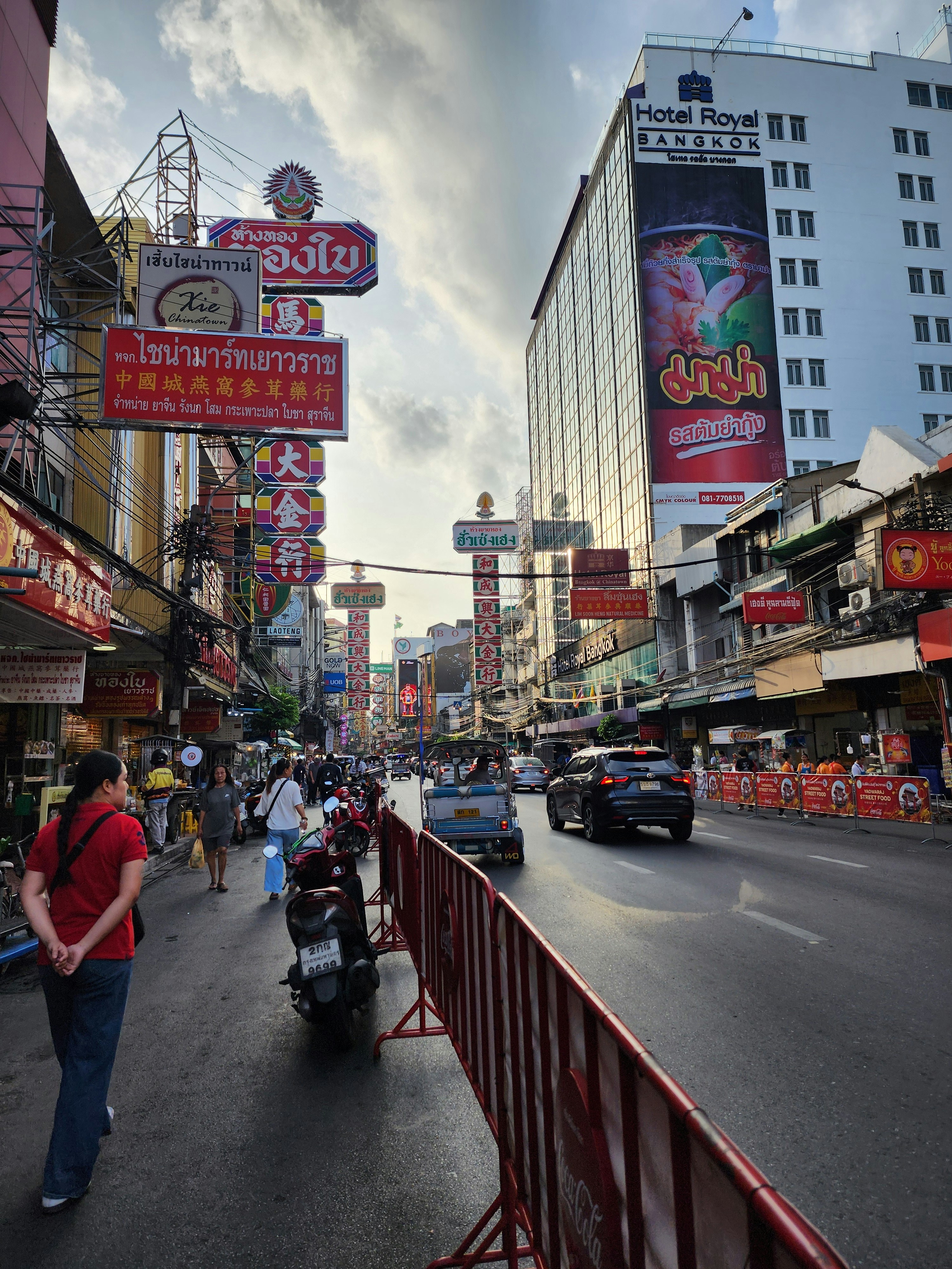 Busy Bangkok street lined with shop signs and motorbikes where English teachers commute to language centers