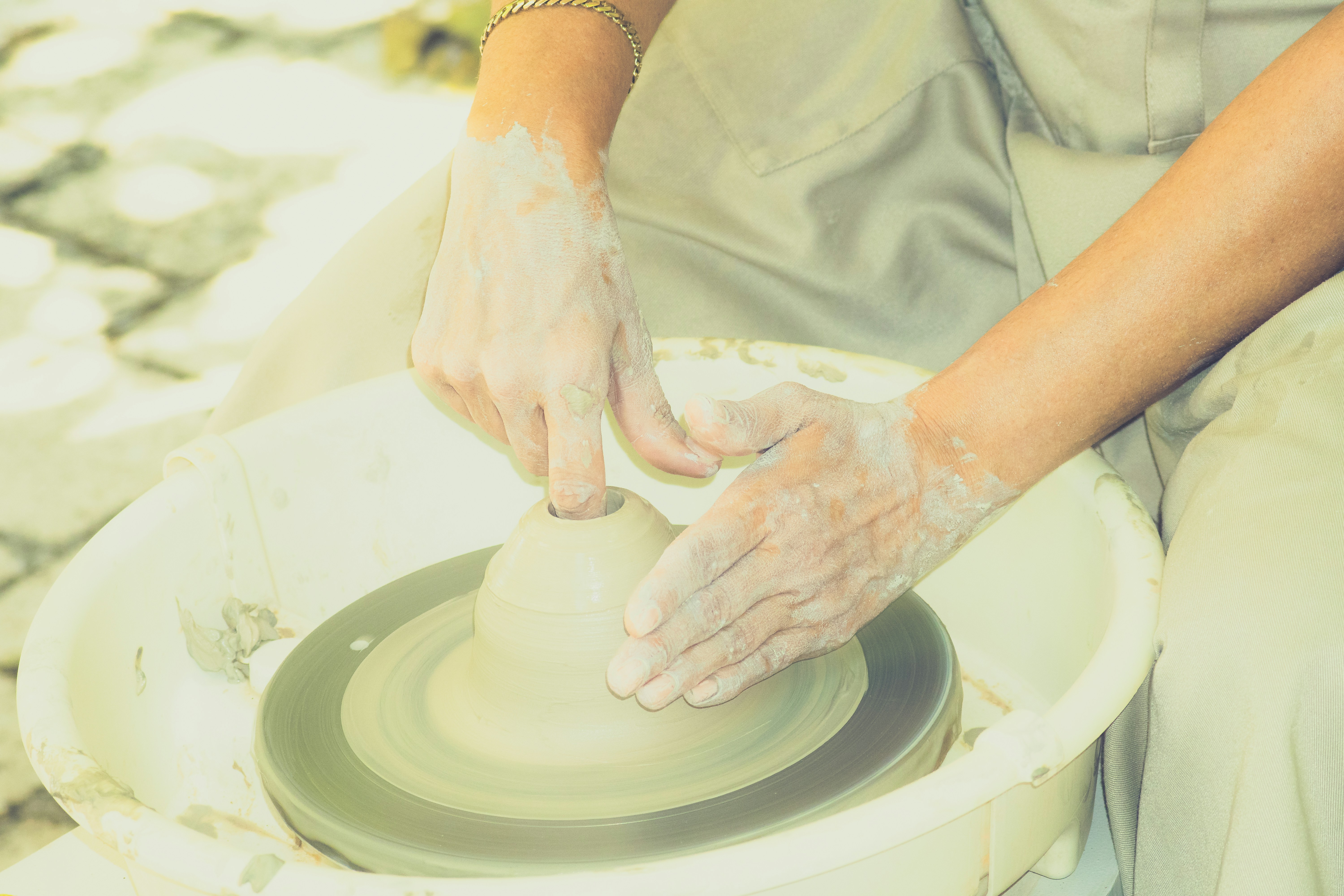 Hands shaping clay on a pottery wheel
