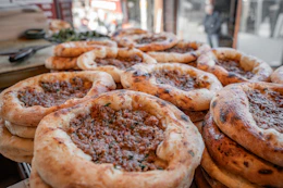 Freshly baked meat pies stacked on a counter.