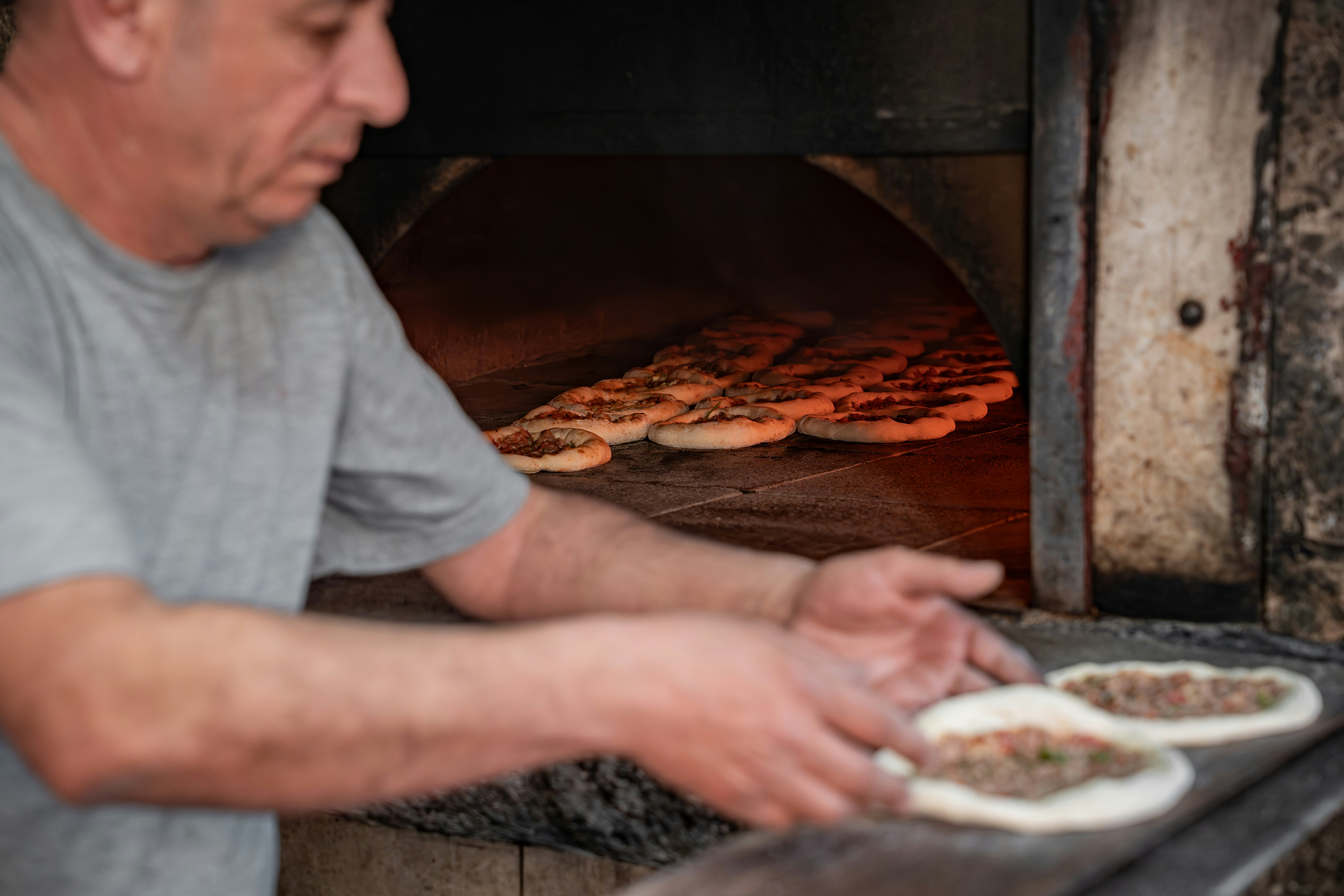 Baker placing pizzas into a hot oven
