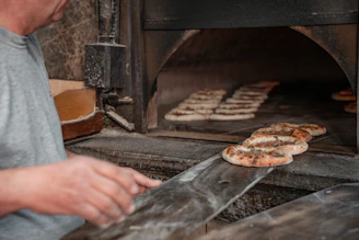 Baker removing flatbread from a stone oven.