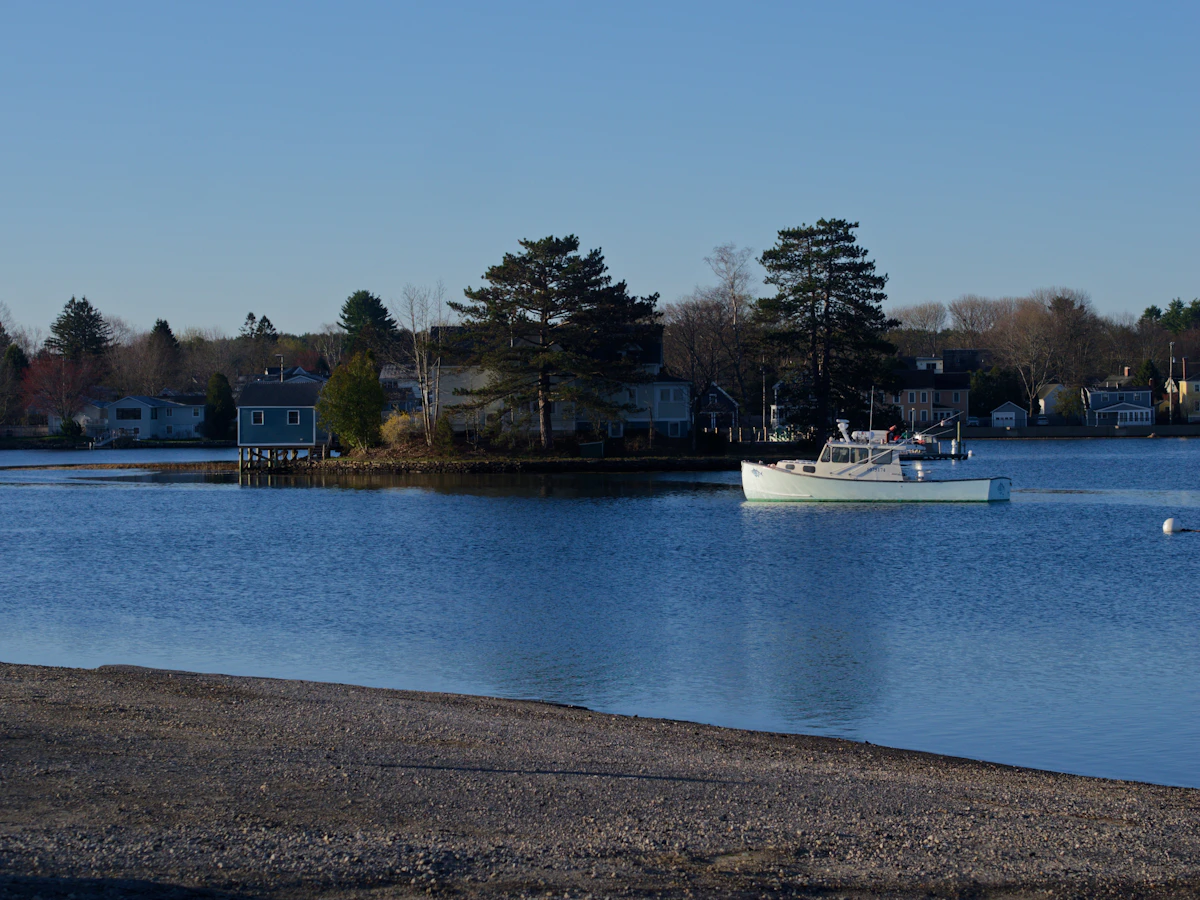 Boat moored in a calm harbour beside a row of waterfront houses in winter