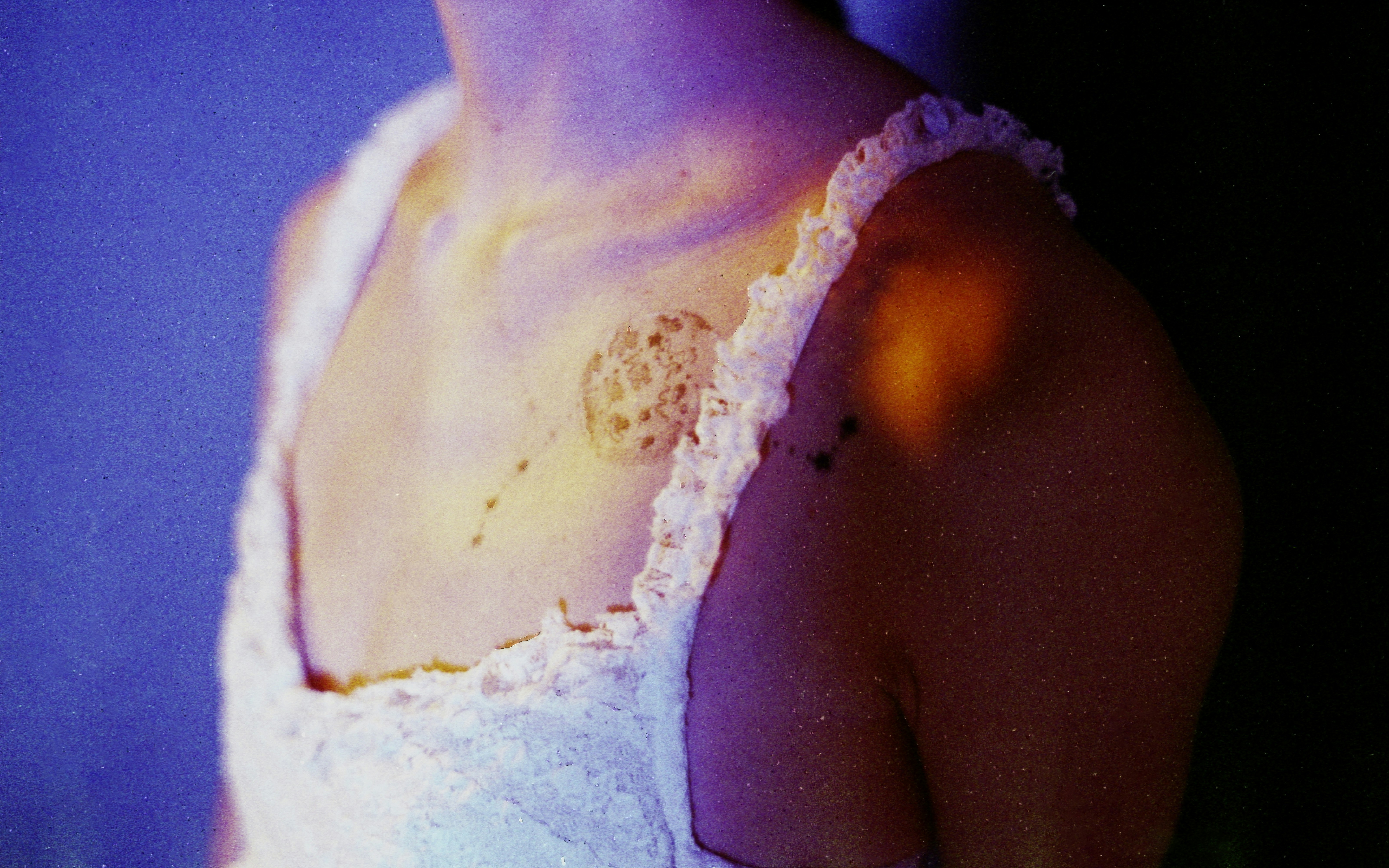 Woman's shoulder with colorful light and tattoo.