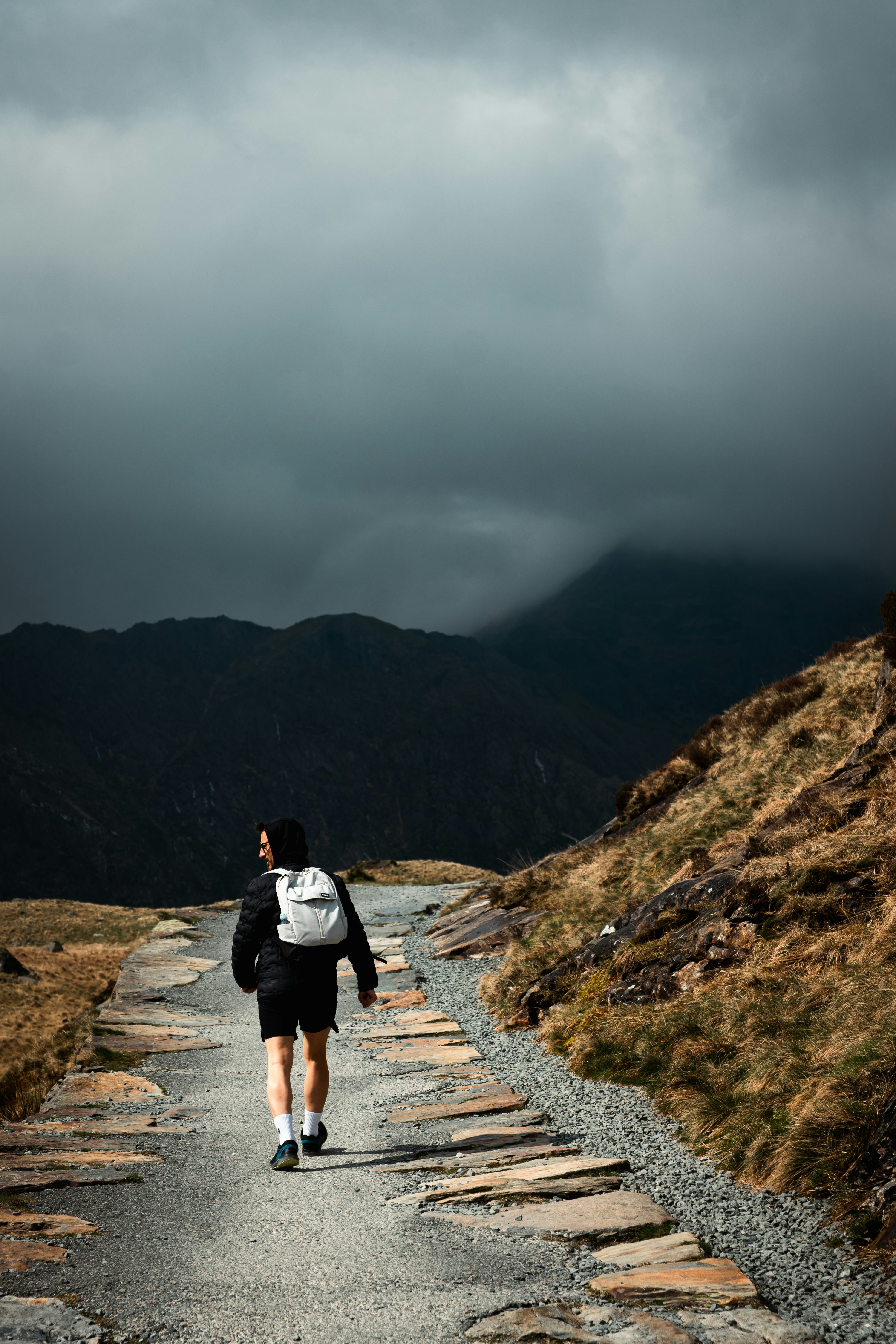 Une personne marche sur un chemin de pierre montant une montagne.