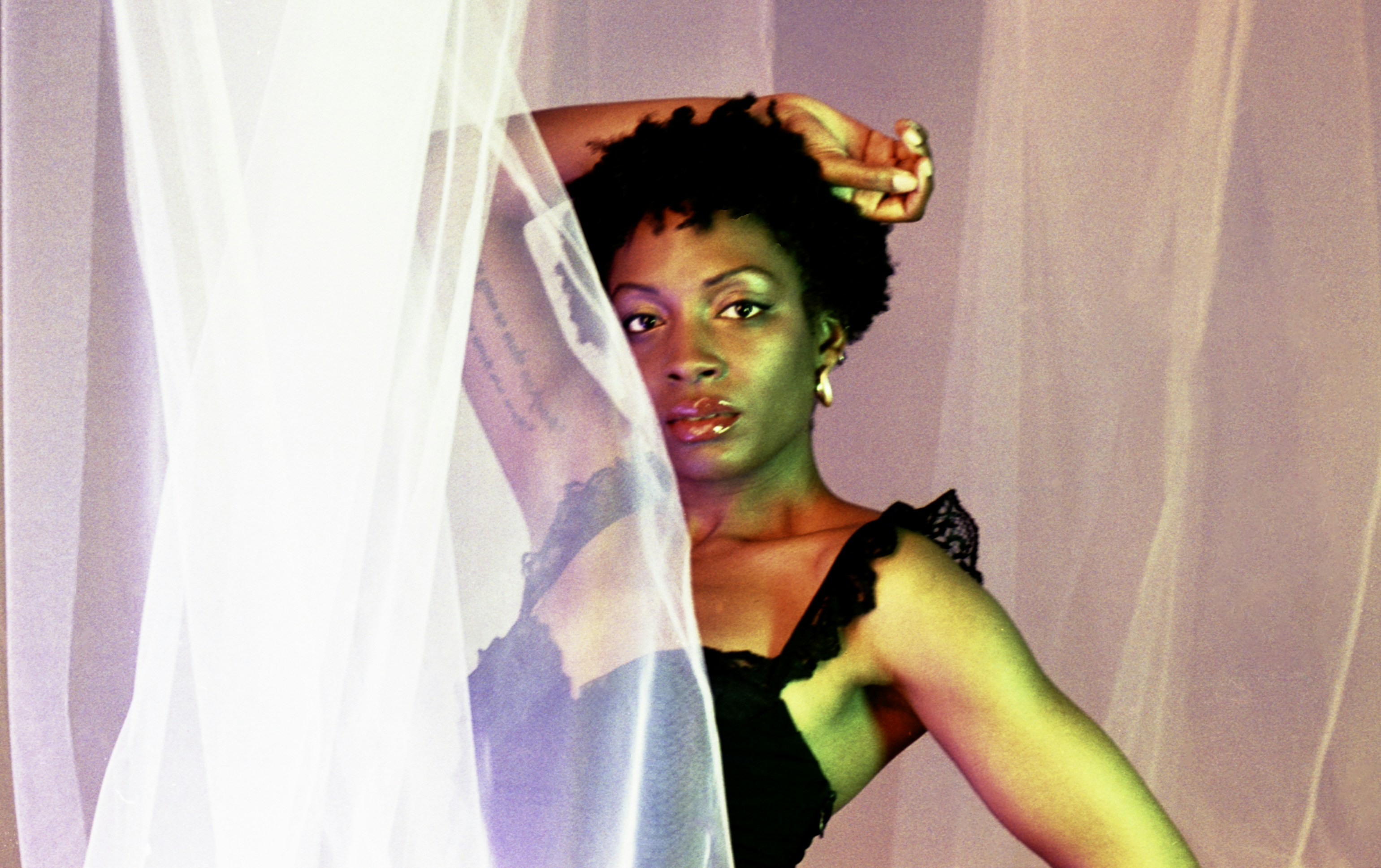 A woman with dark curly hair behind sheer fabric