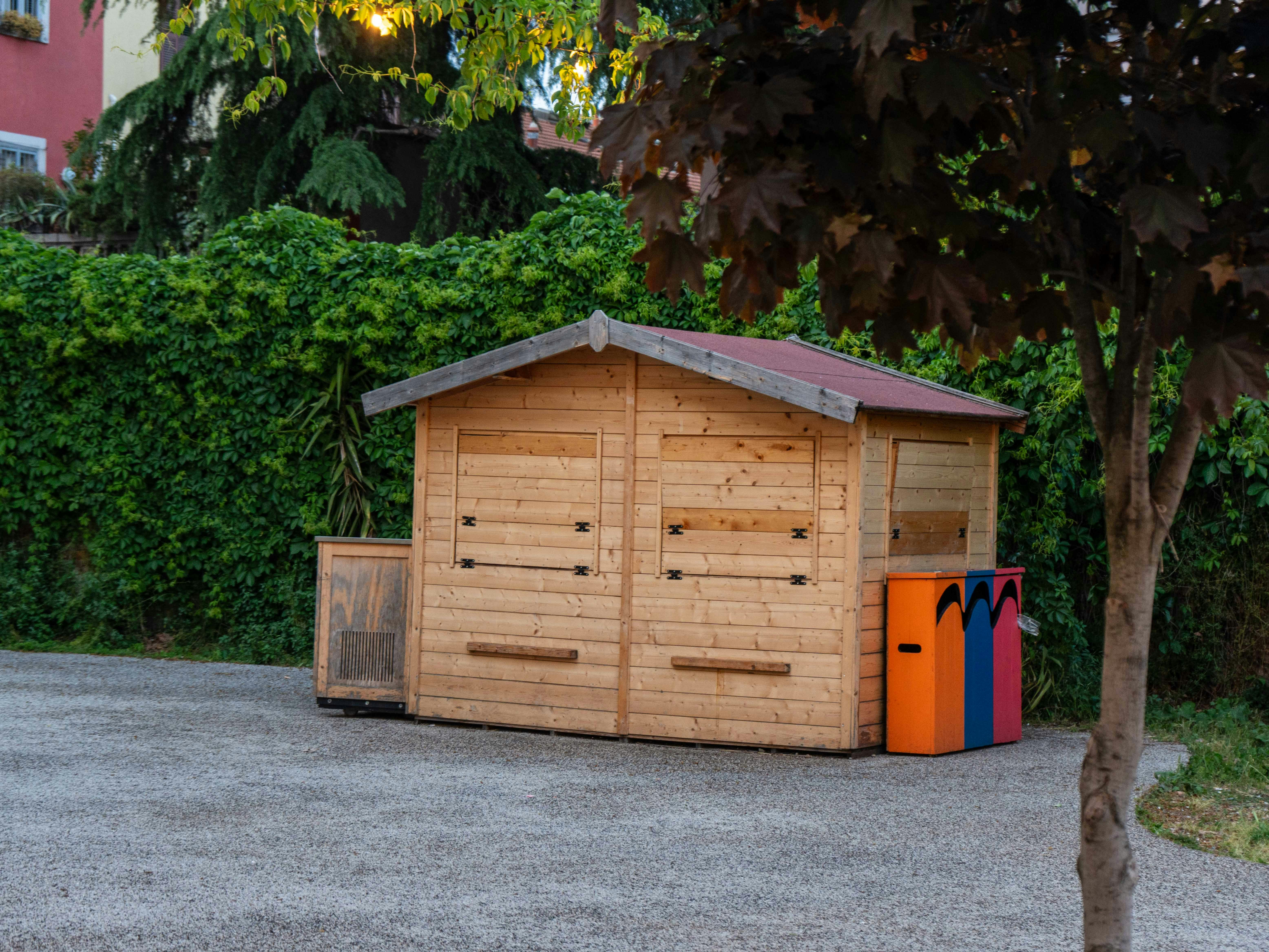 Wooden shed with colorful trash bins nearby