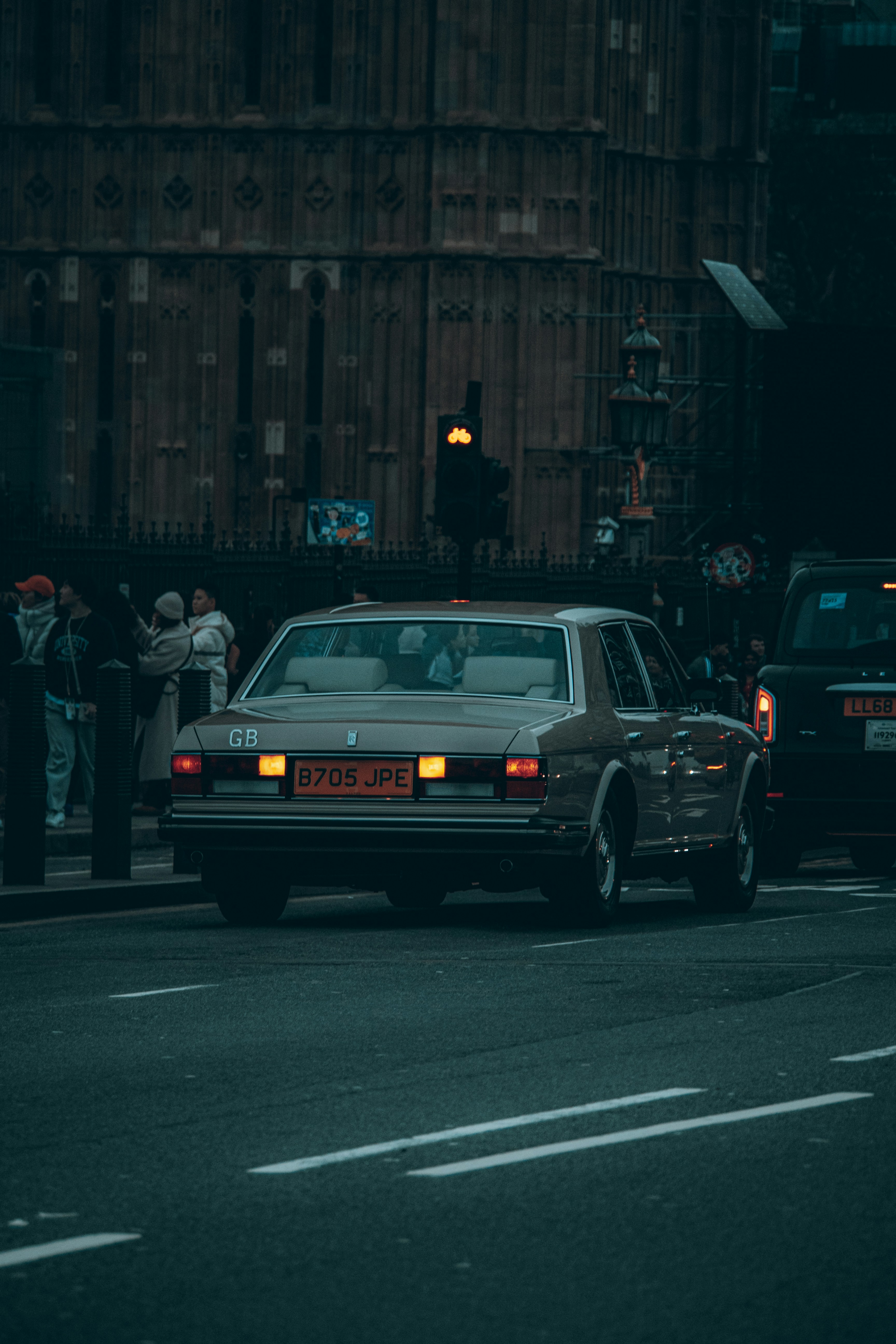 Vintage car driving on a city street at dusk.