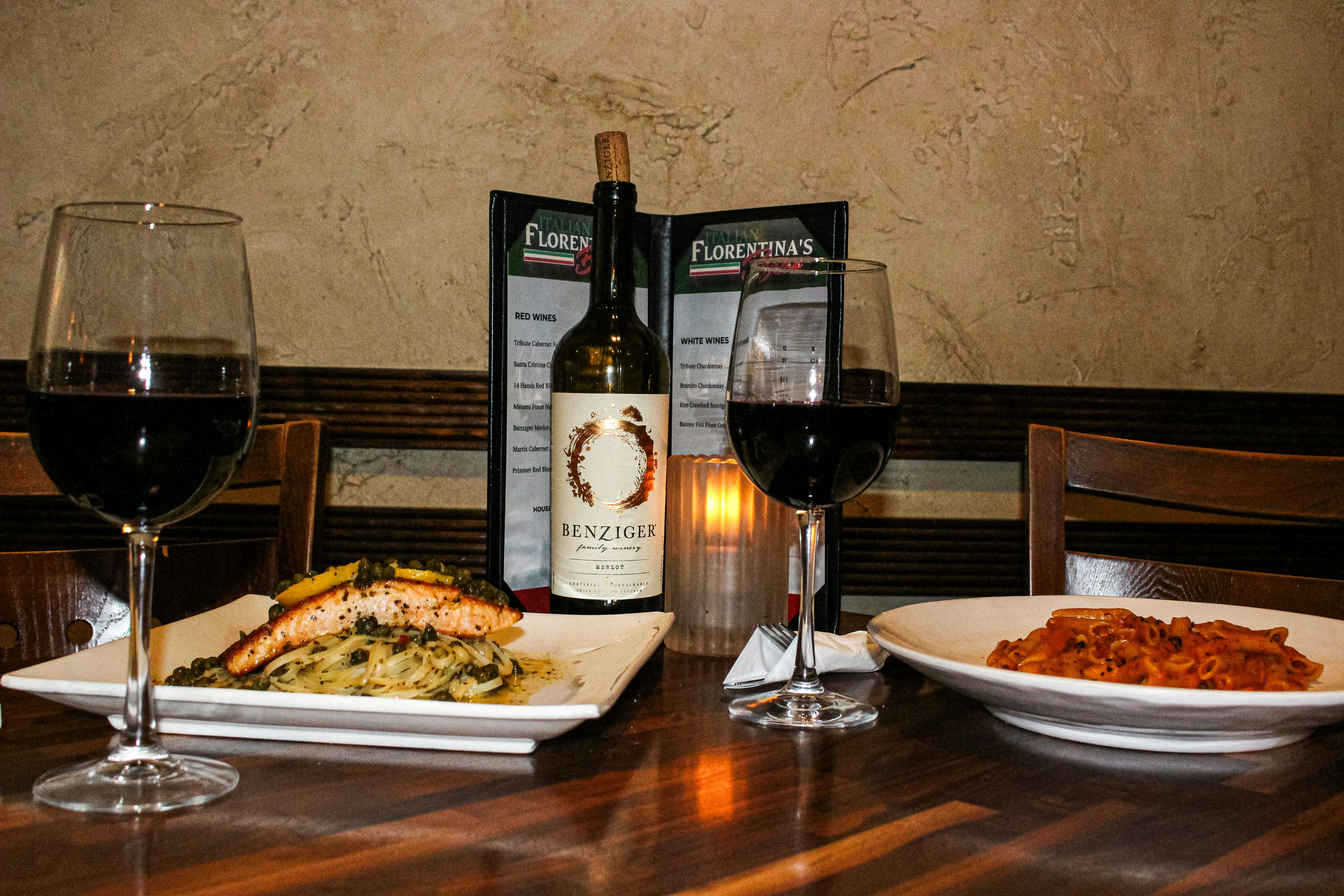 Two glasses of red wine and a meal on table.