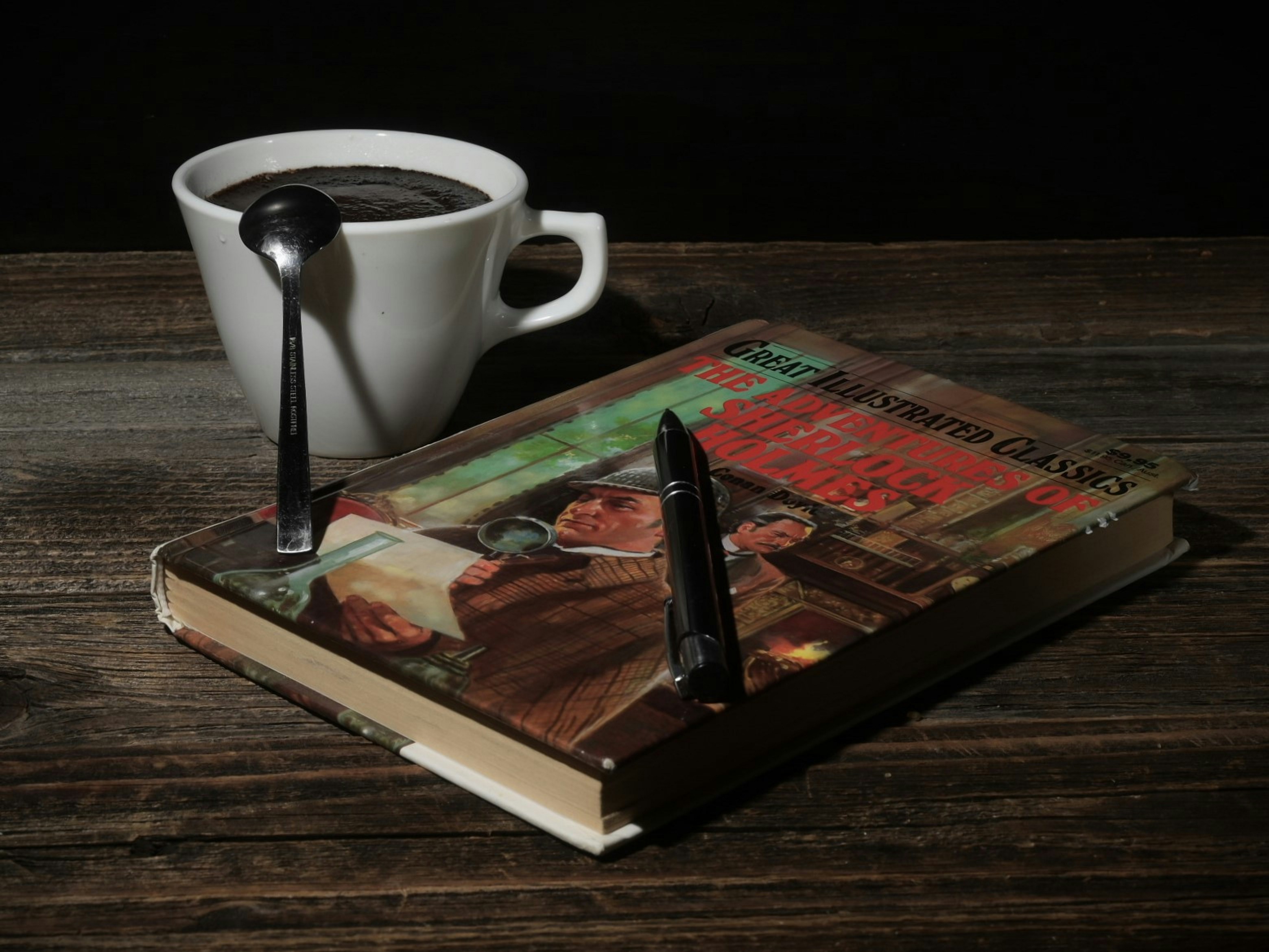 A vintage book and mug of coffee rest on wood.