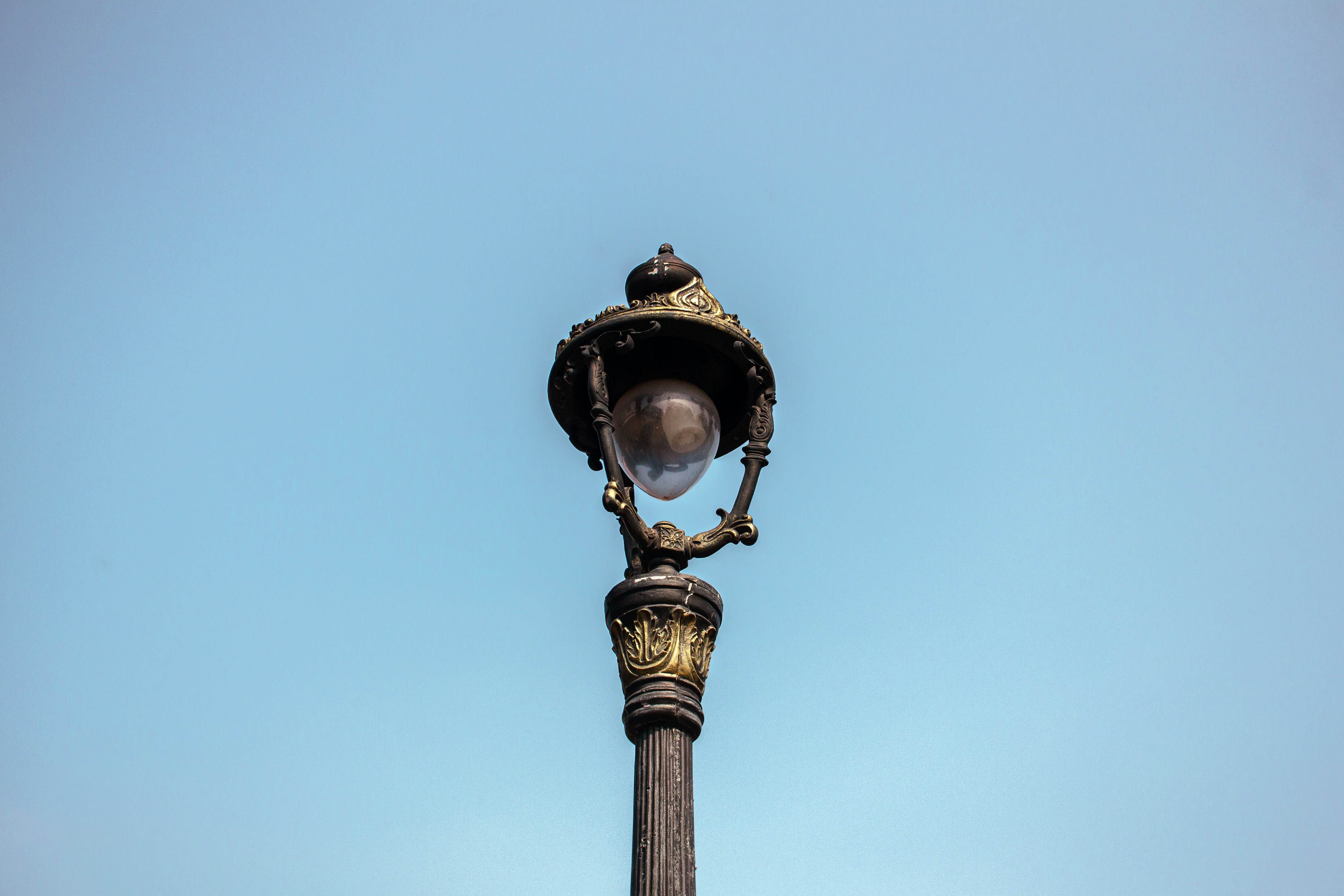 An ornate vintage street lamp against a clear blue sky
