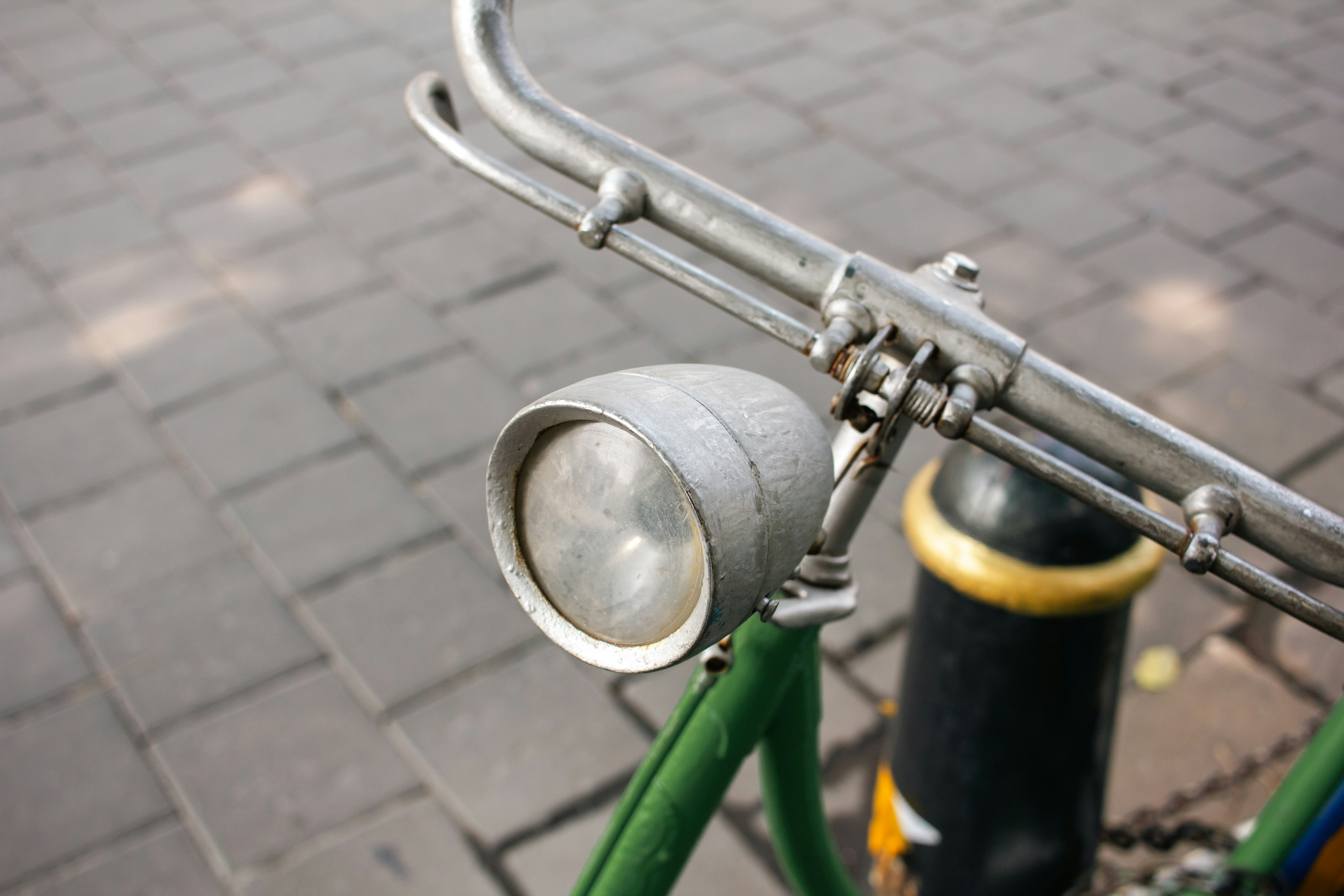 Close-up of an old bicycle headlight on handlebars.