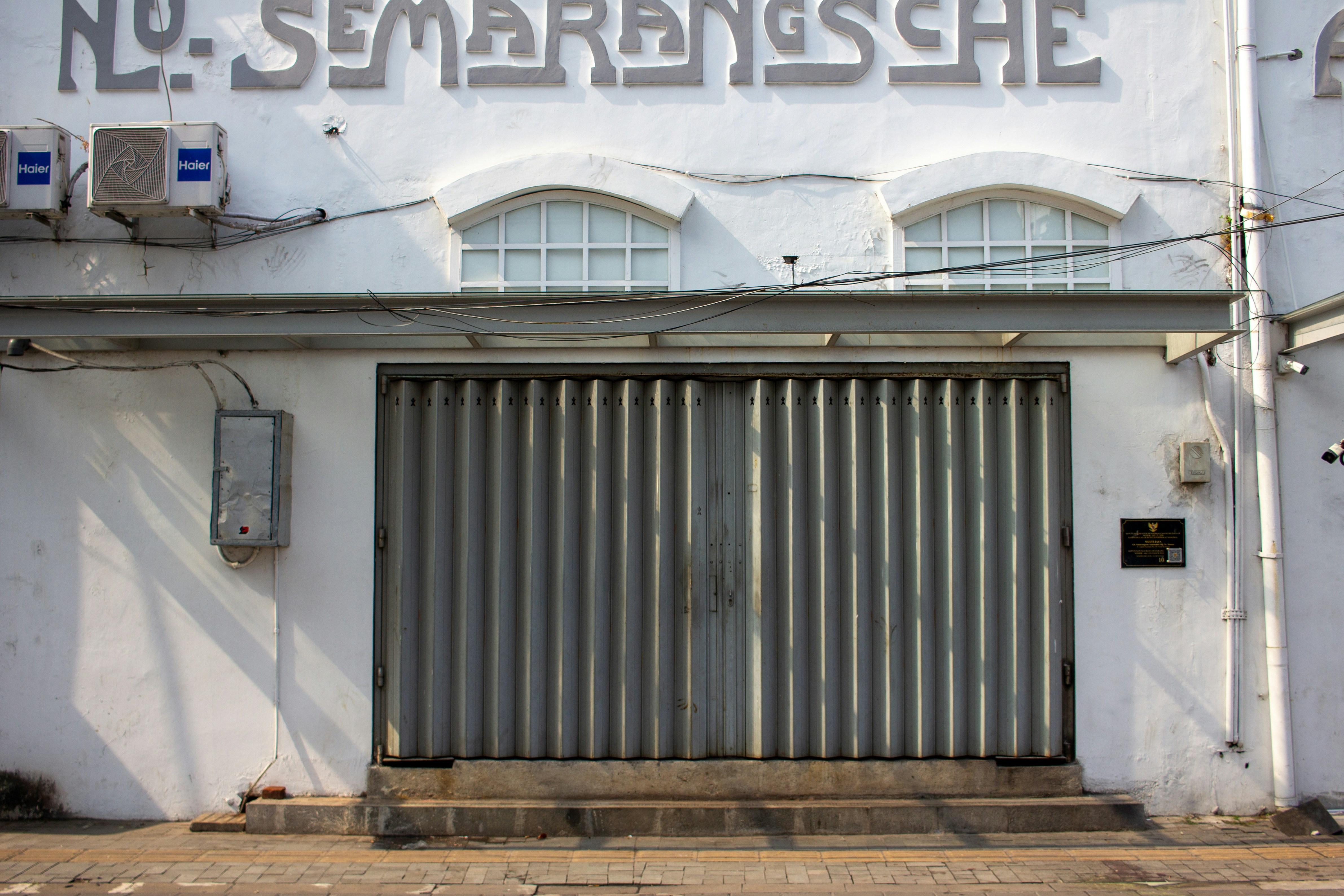 Closed metal gate on a white building facade.