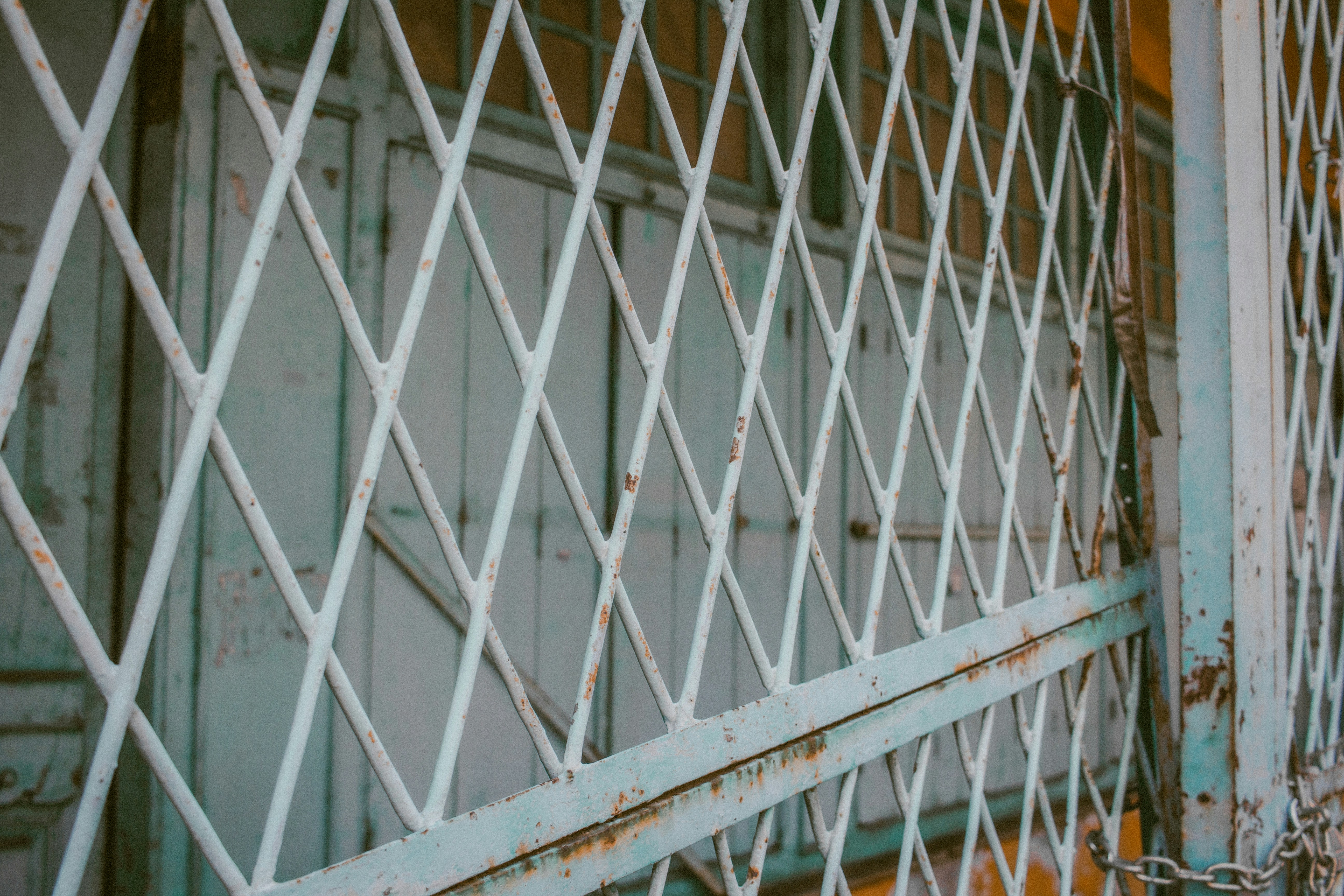 Close-up of a weathered white metal security gate.