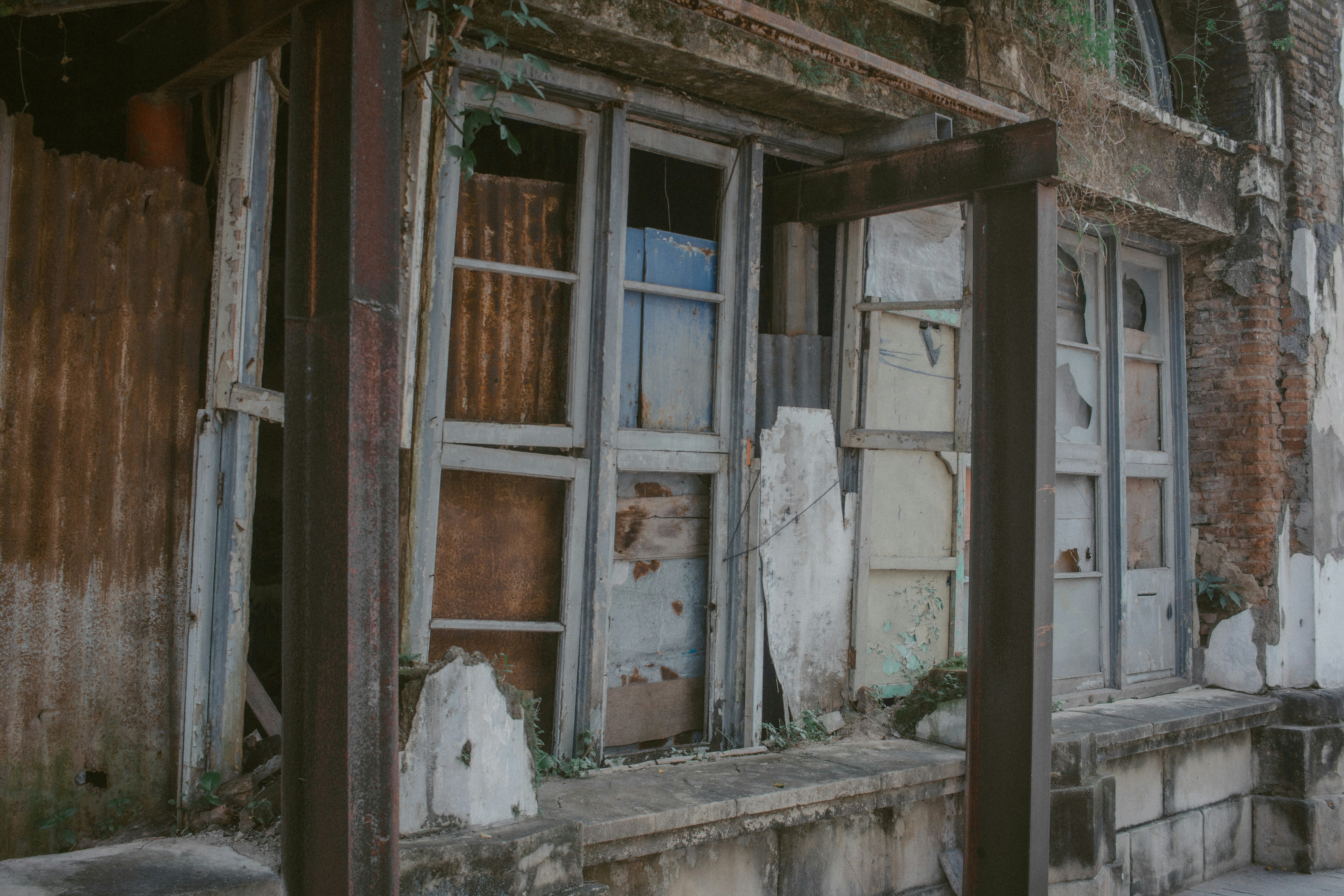 Dilapidated building facade with weathered windows and corrugated metal