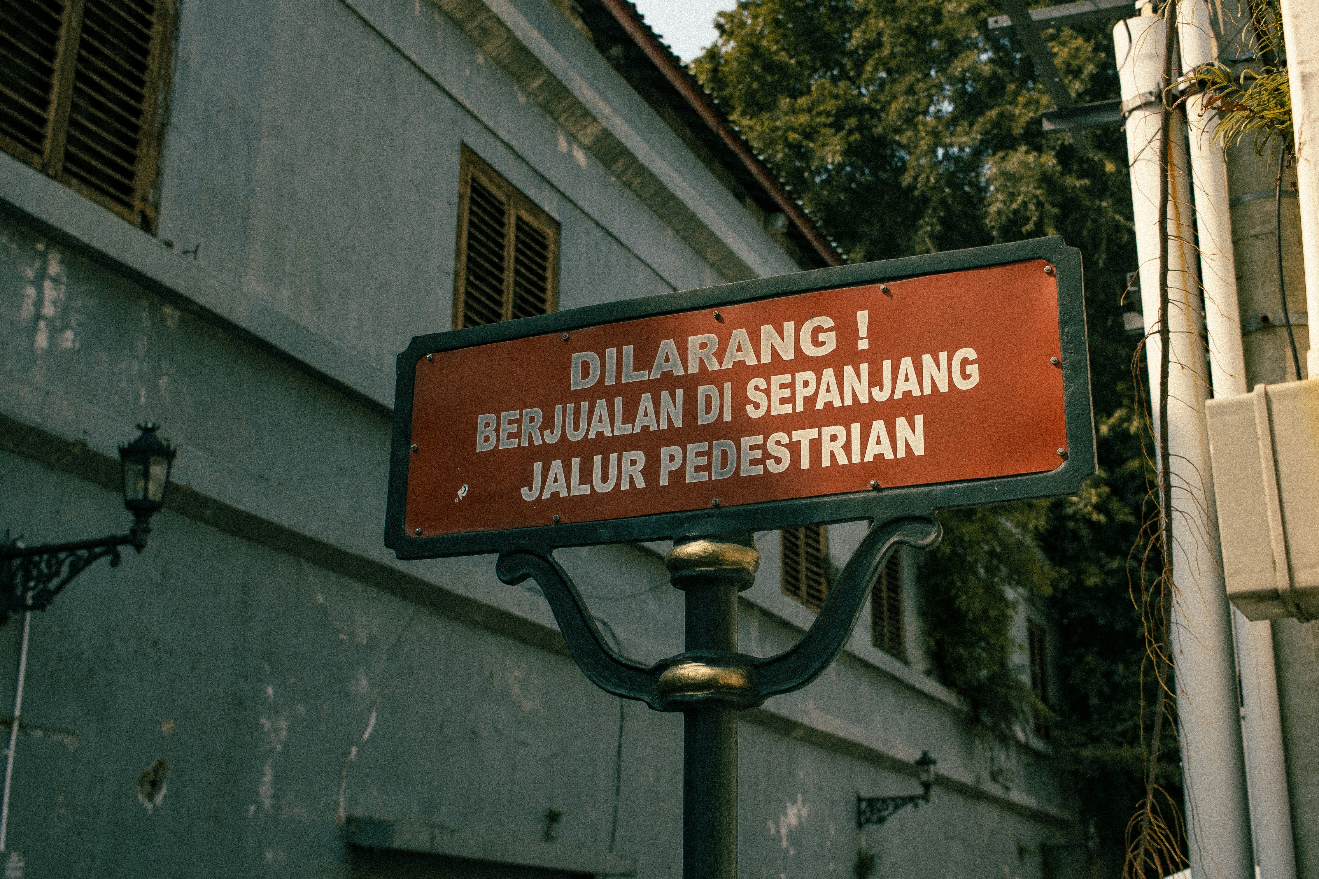 Red sign prohibiting street vendors on pedestrian path.