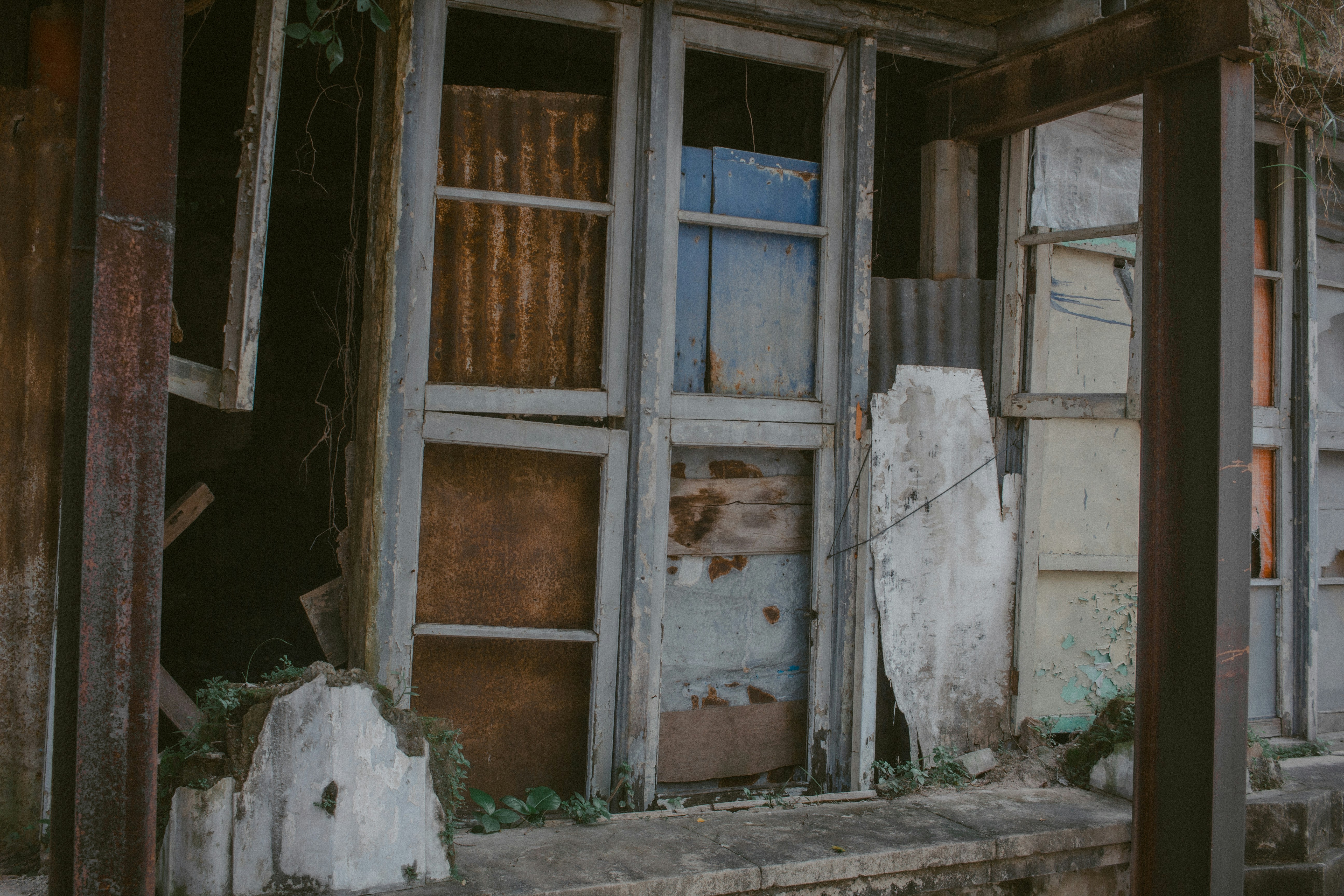 Dilapidated building with broken windows and weathered facade.