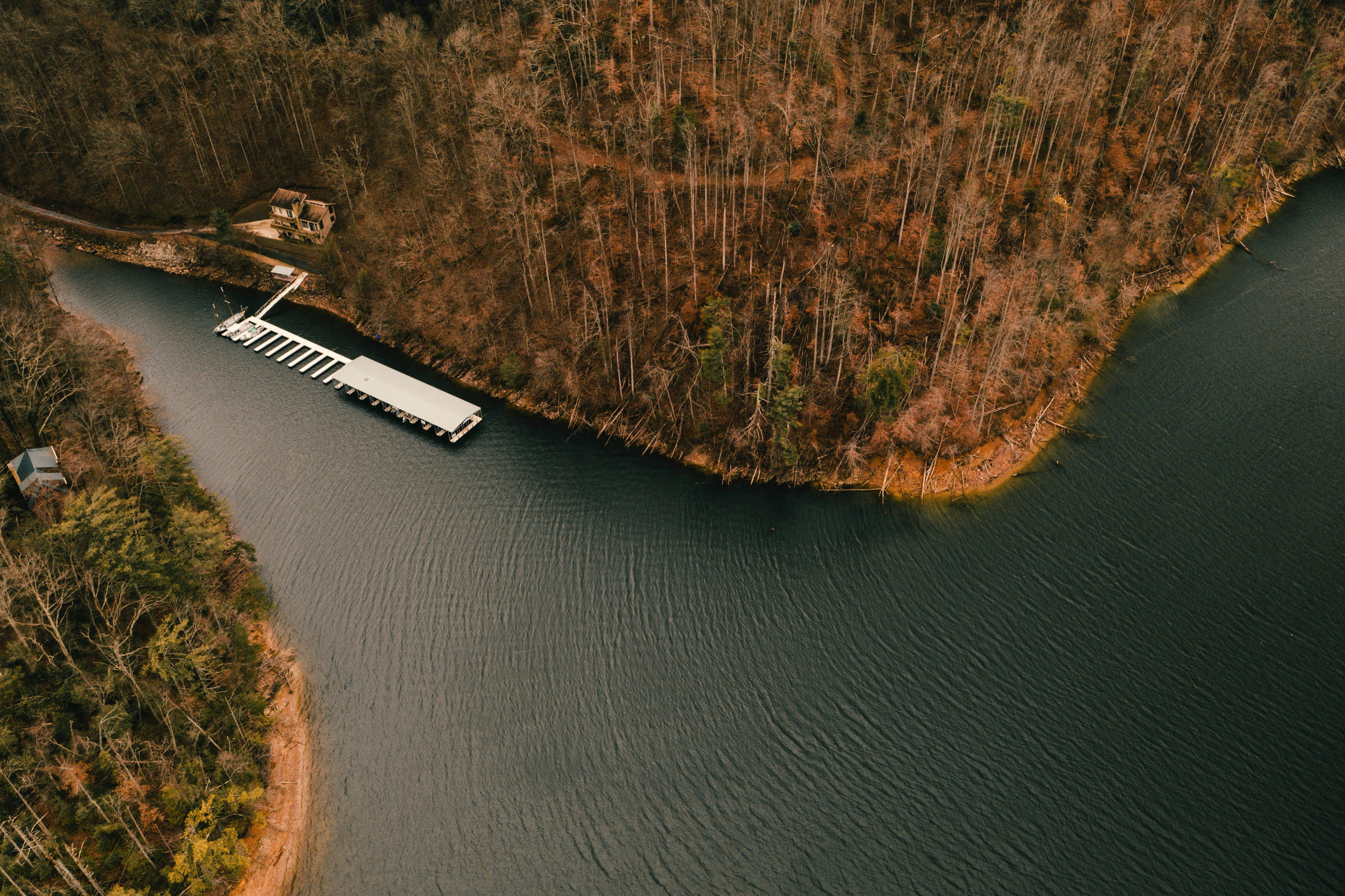 Dock on a dark lake surrounded by autumn trees