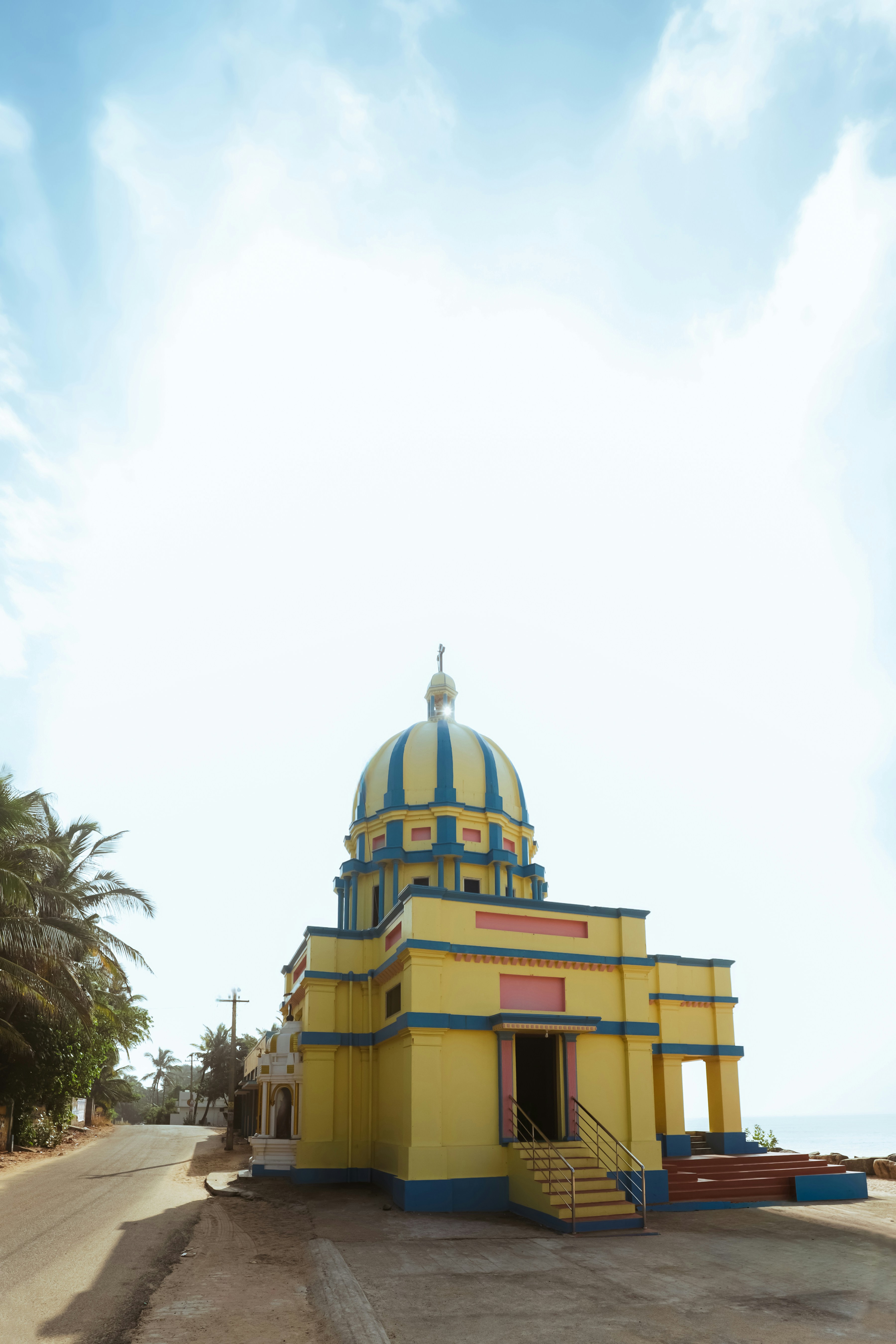 Um edifício colorido com cúpula amarela e azul à beira do mar.