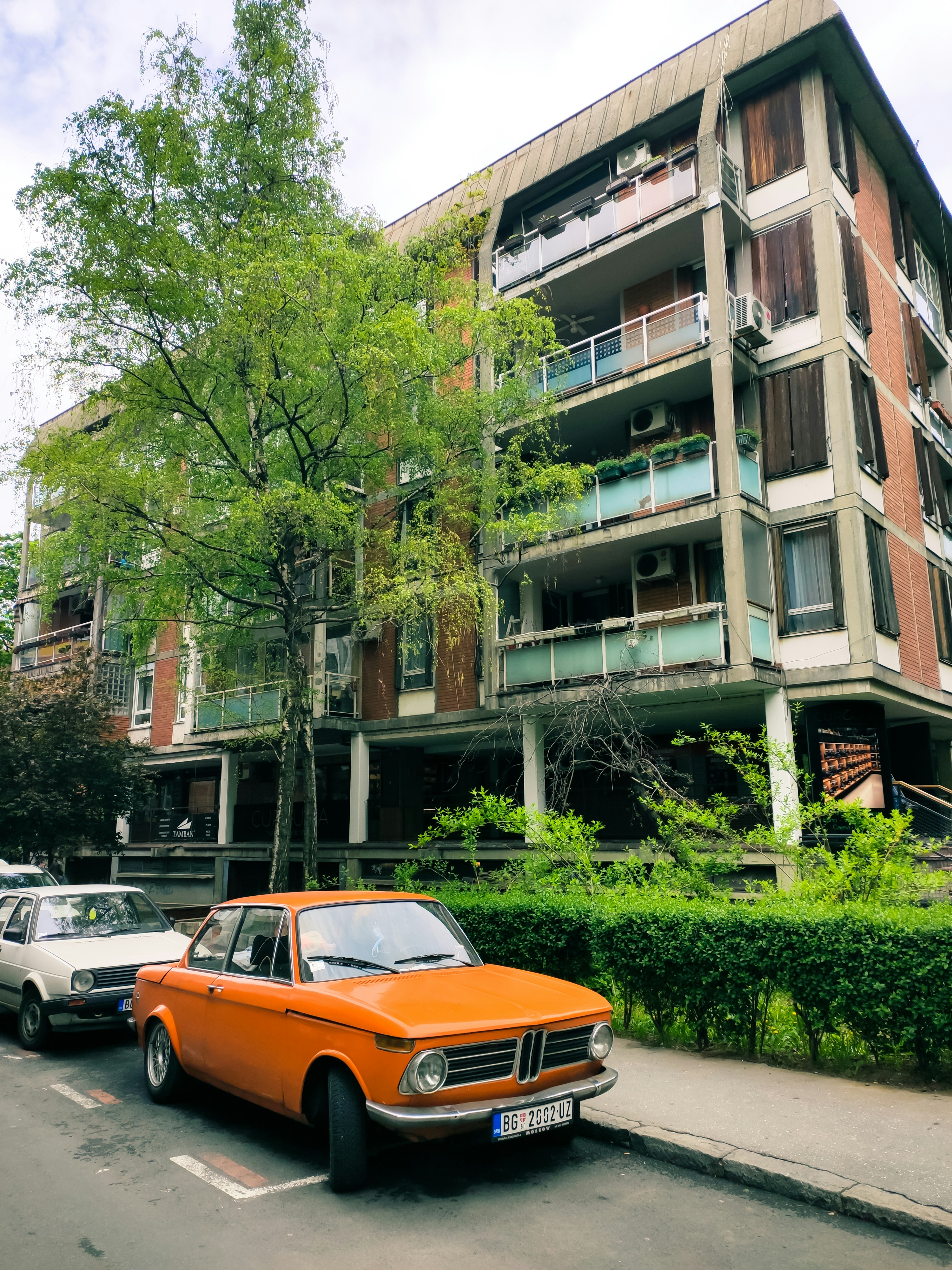 Orange car parked on street beside apartment building