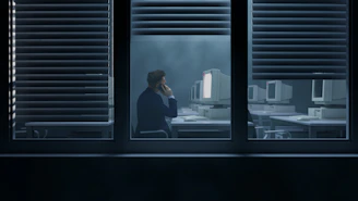 Man on phone at desk with old computers