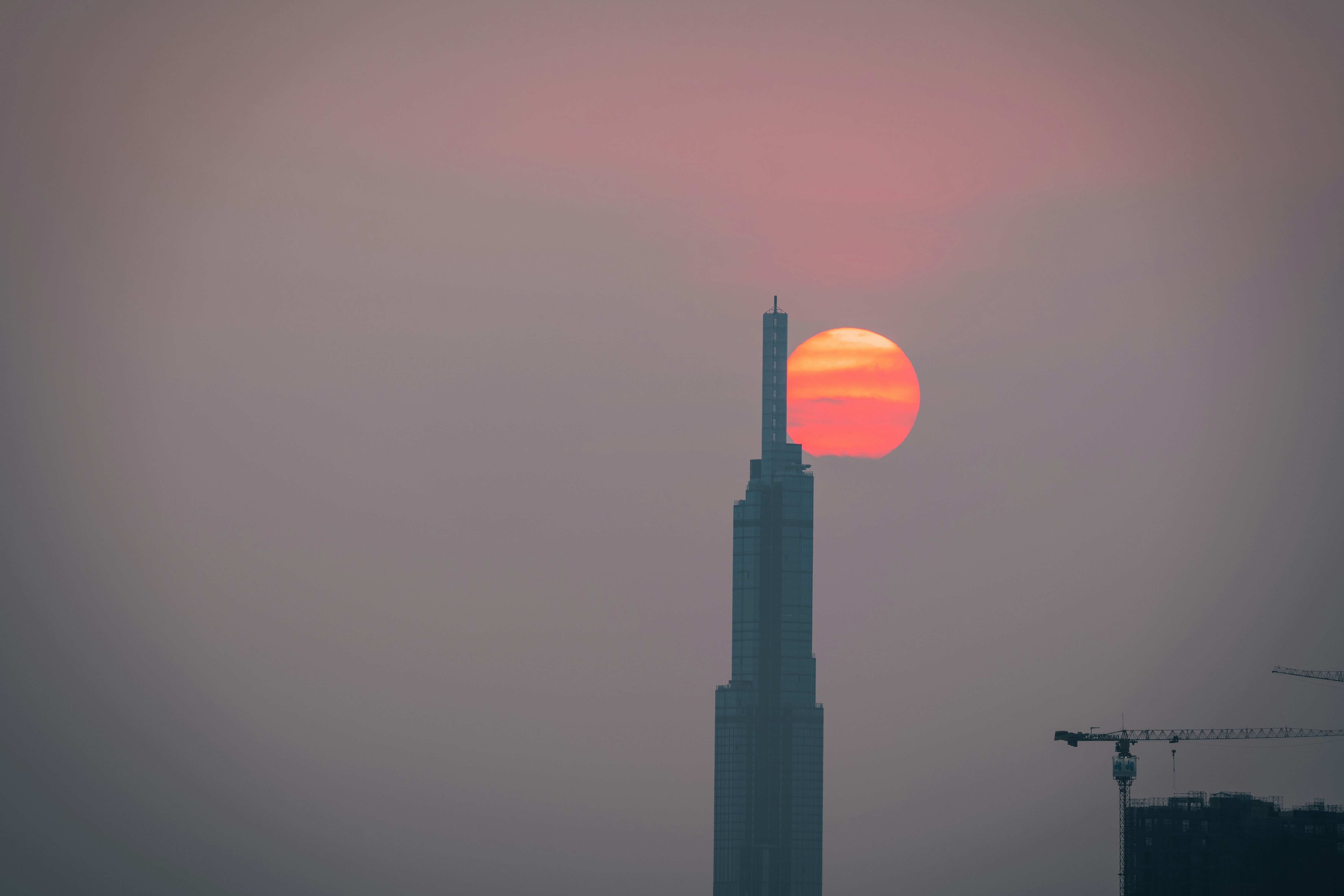 Red sun sets behind the Landmark 81 - the tallest building in Vietnam
