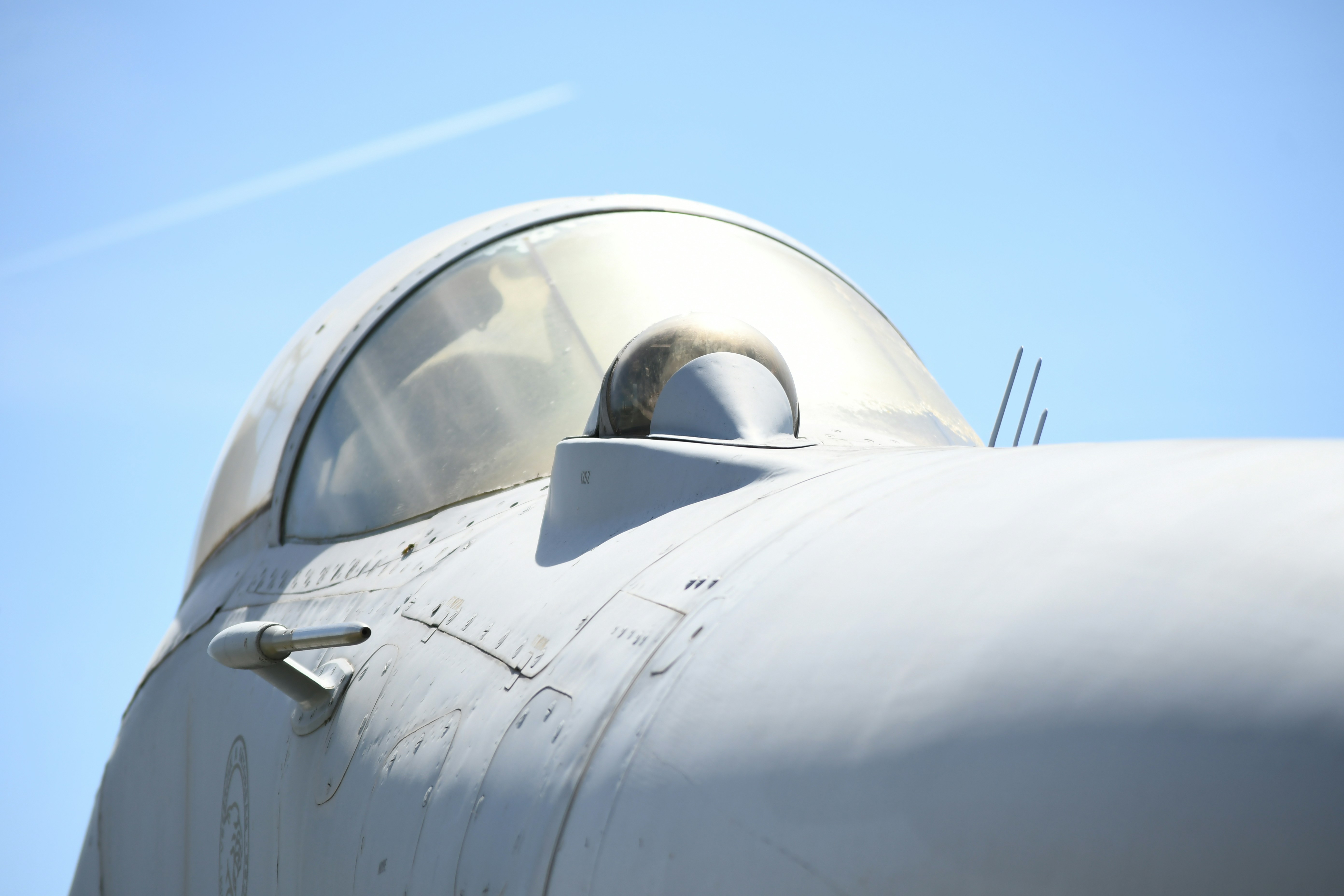 Close-up of a fighter jet cockpit against a blue sky