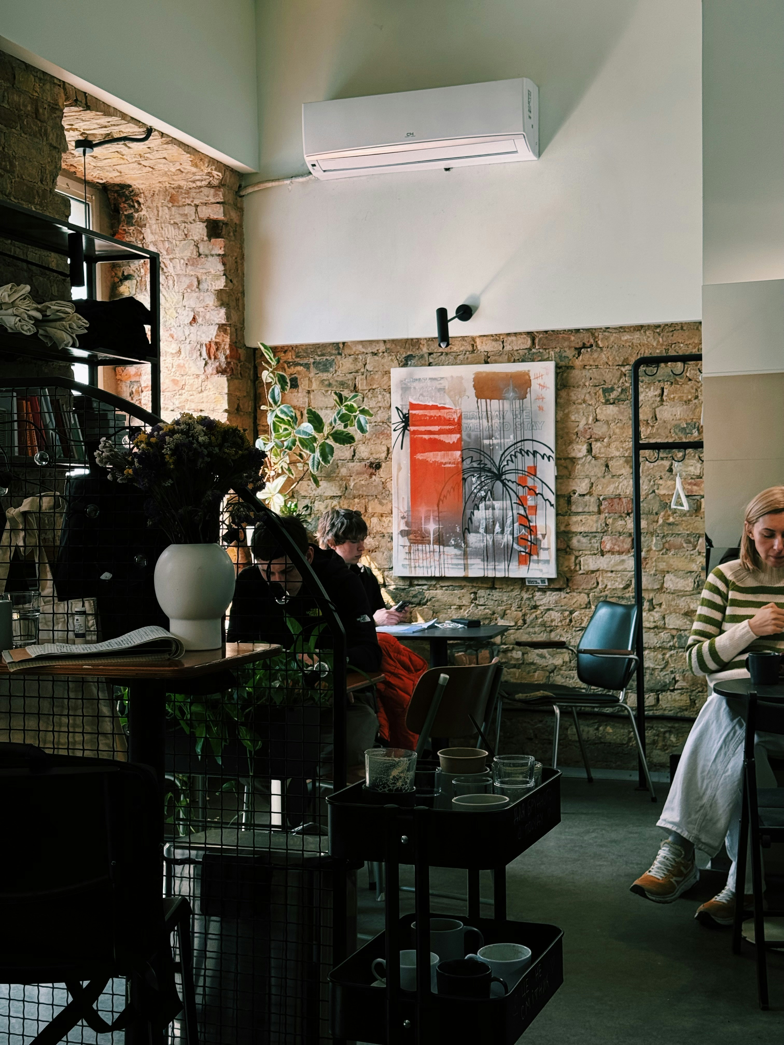 Persone sedute in un caffè con muri di mattoni e opere d'arte.