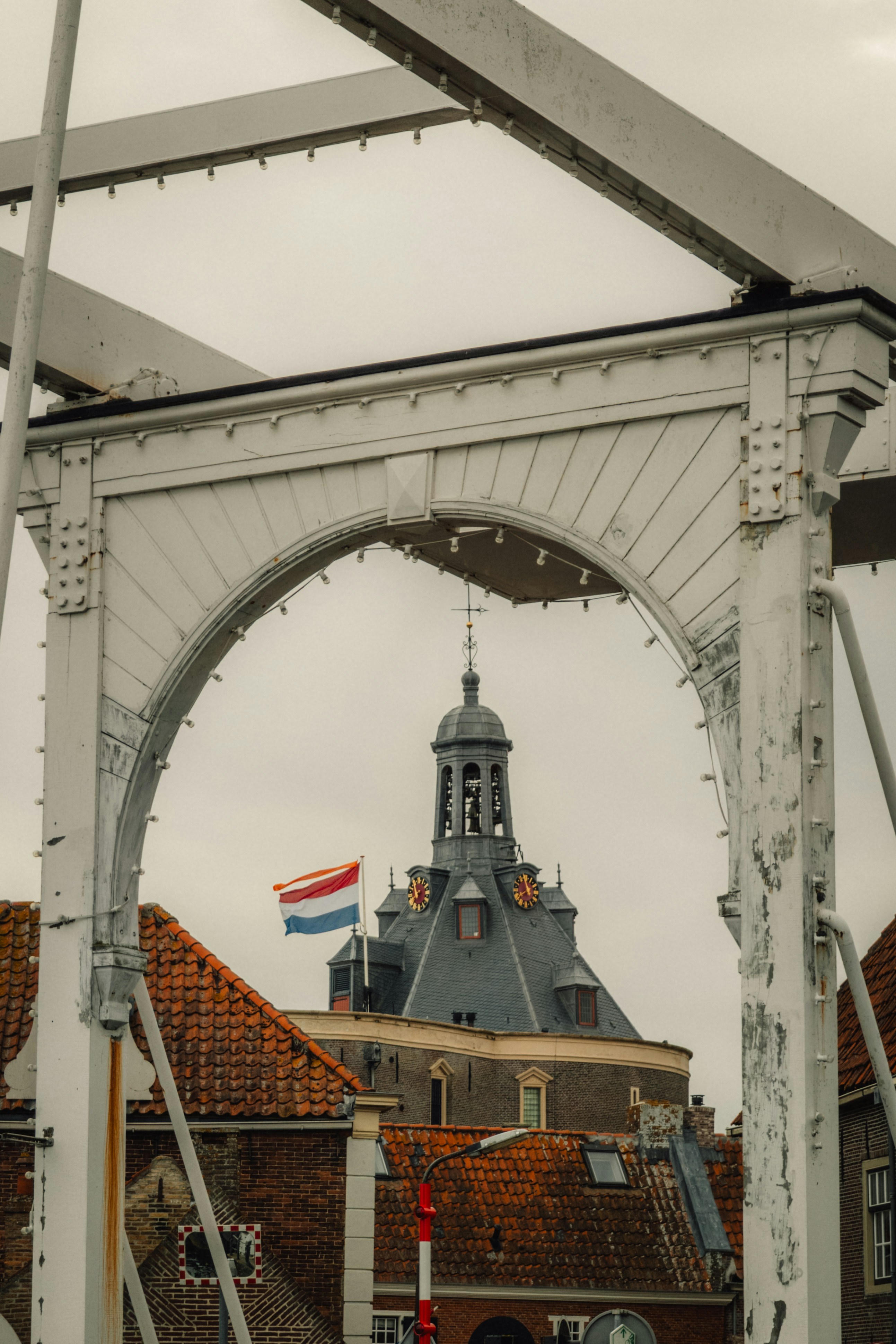 Dutch flag flies over historic building framed by bridge