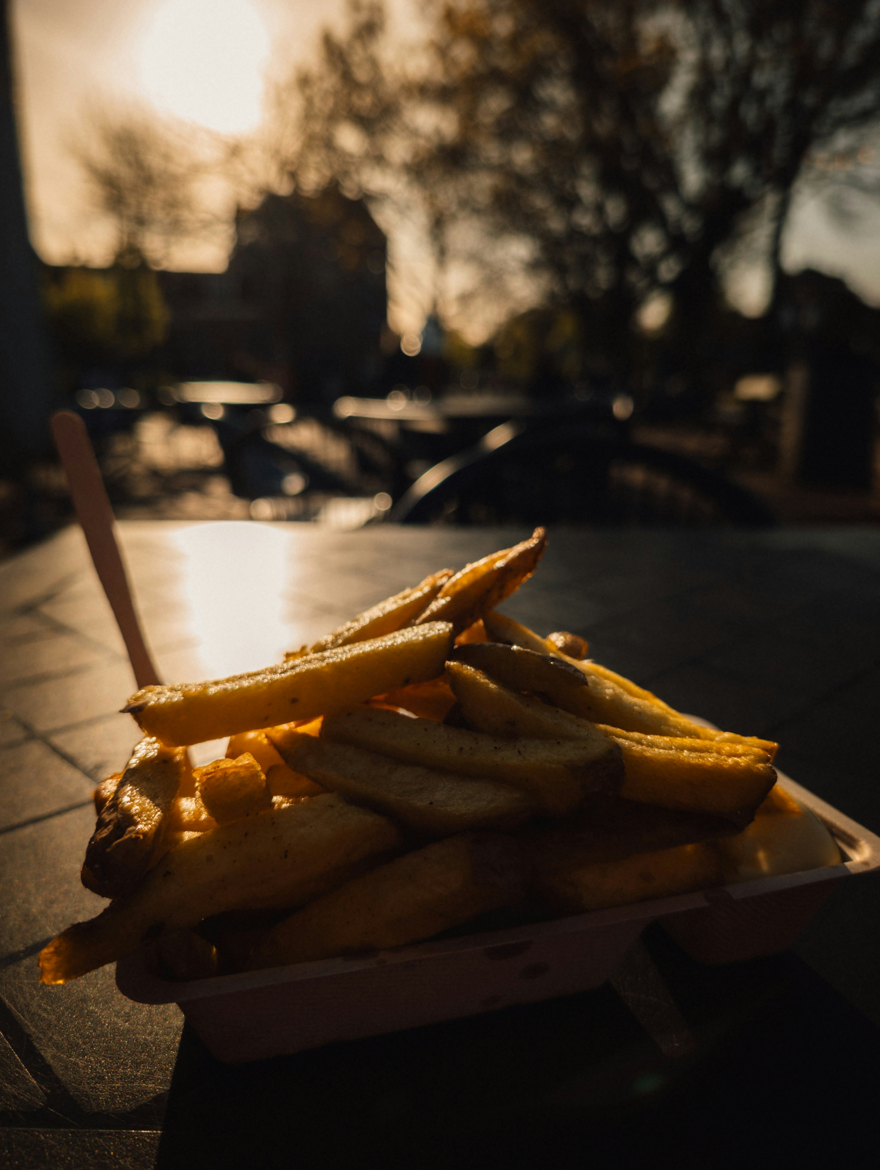 A serving of golden french fries outdoors at sunset