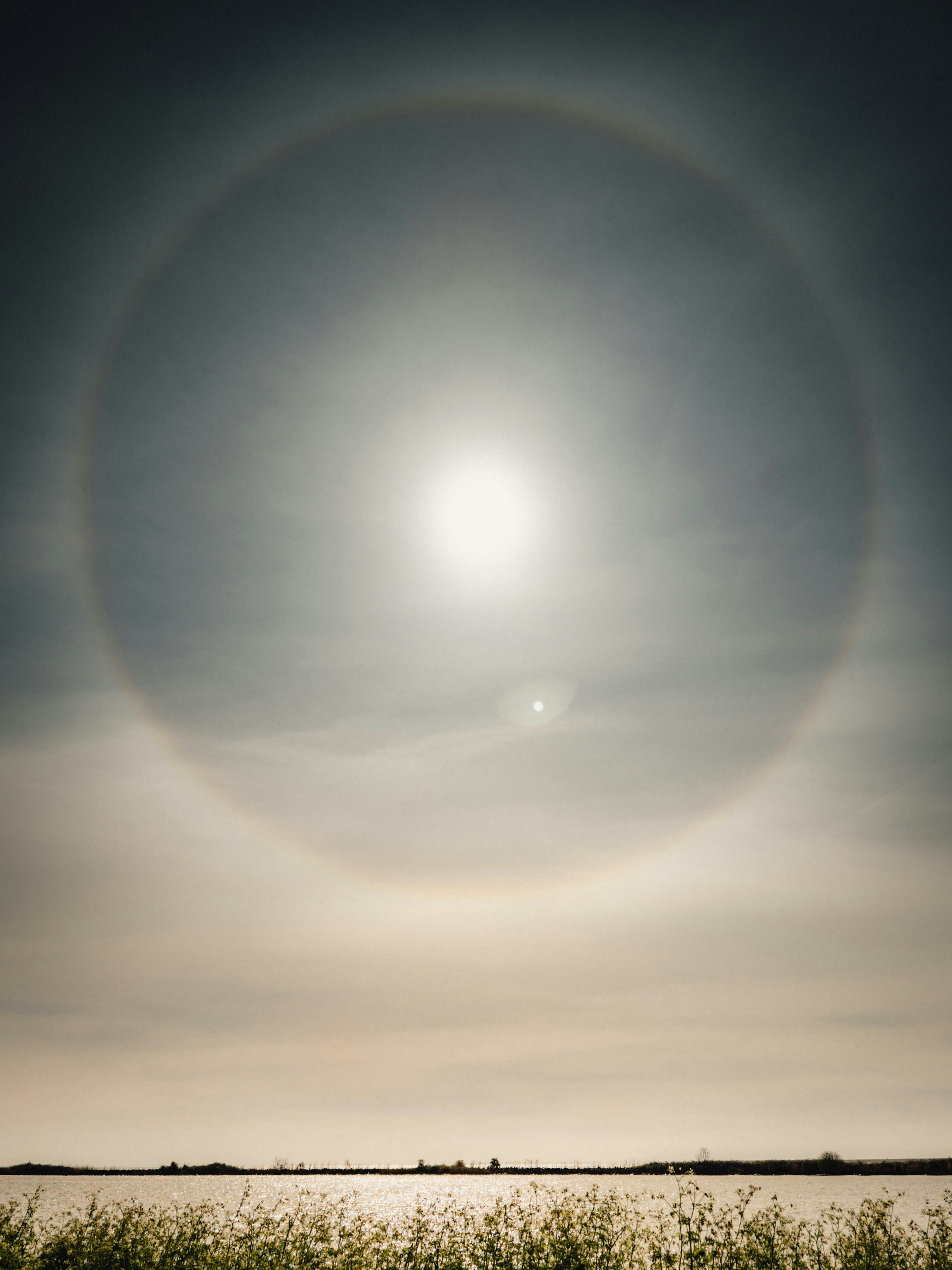A bright sun with a large halo in the sky