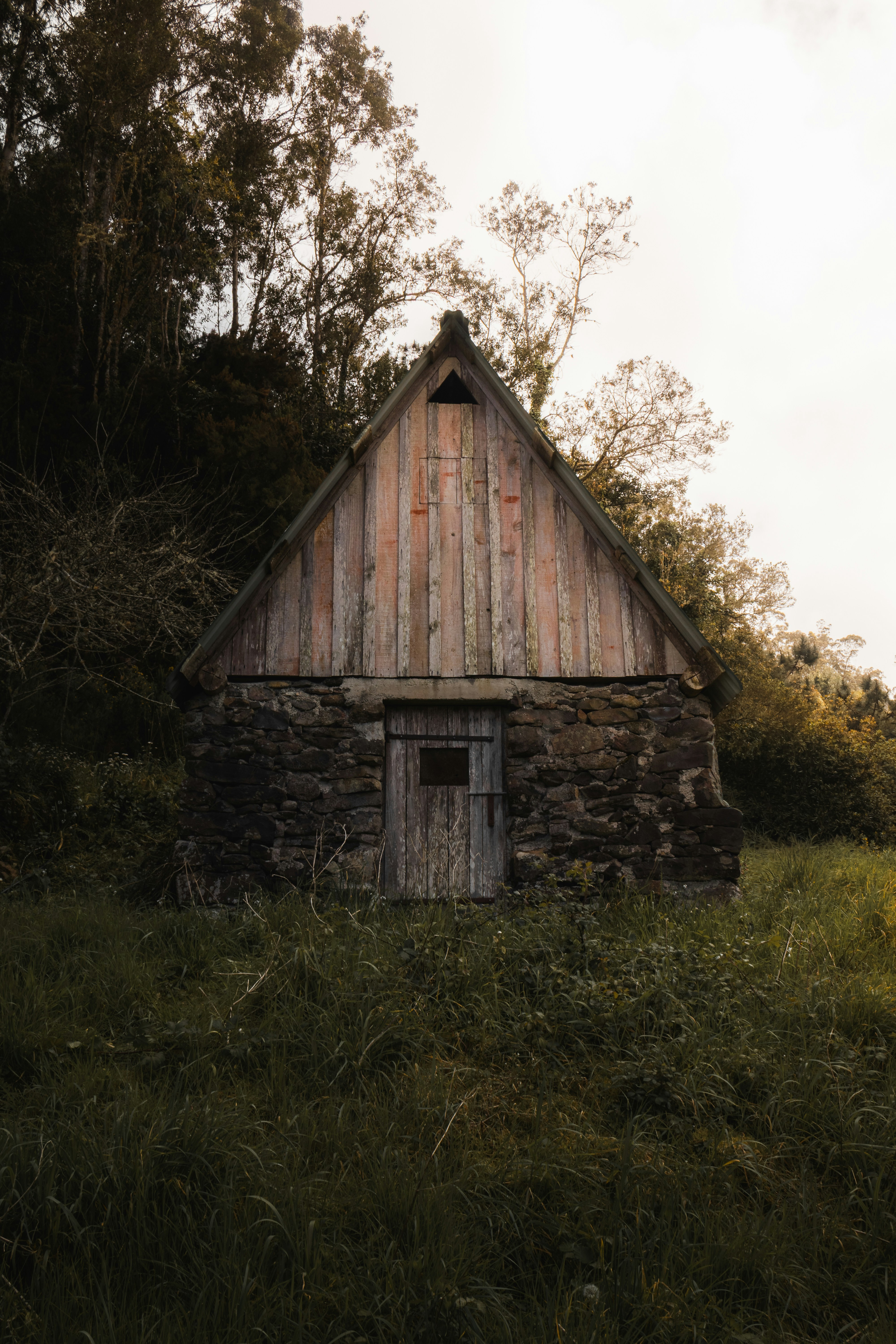 Old stone and wood cabin nestled in grassy hillside.