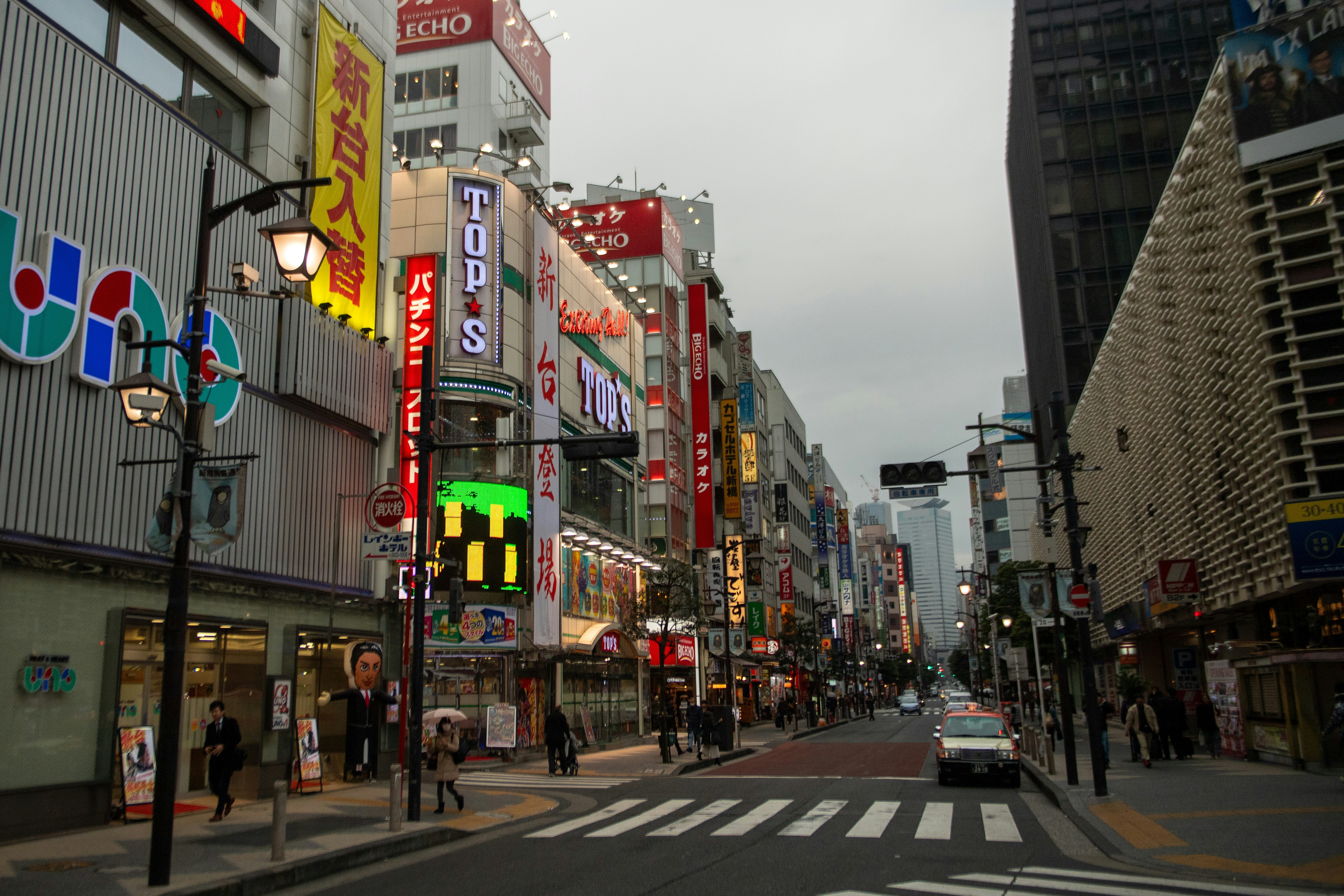 Quiet tree-lined residential backstreet in Tokyo with small cafes and cyclists near a train station in autumn