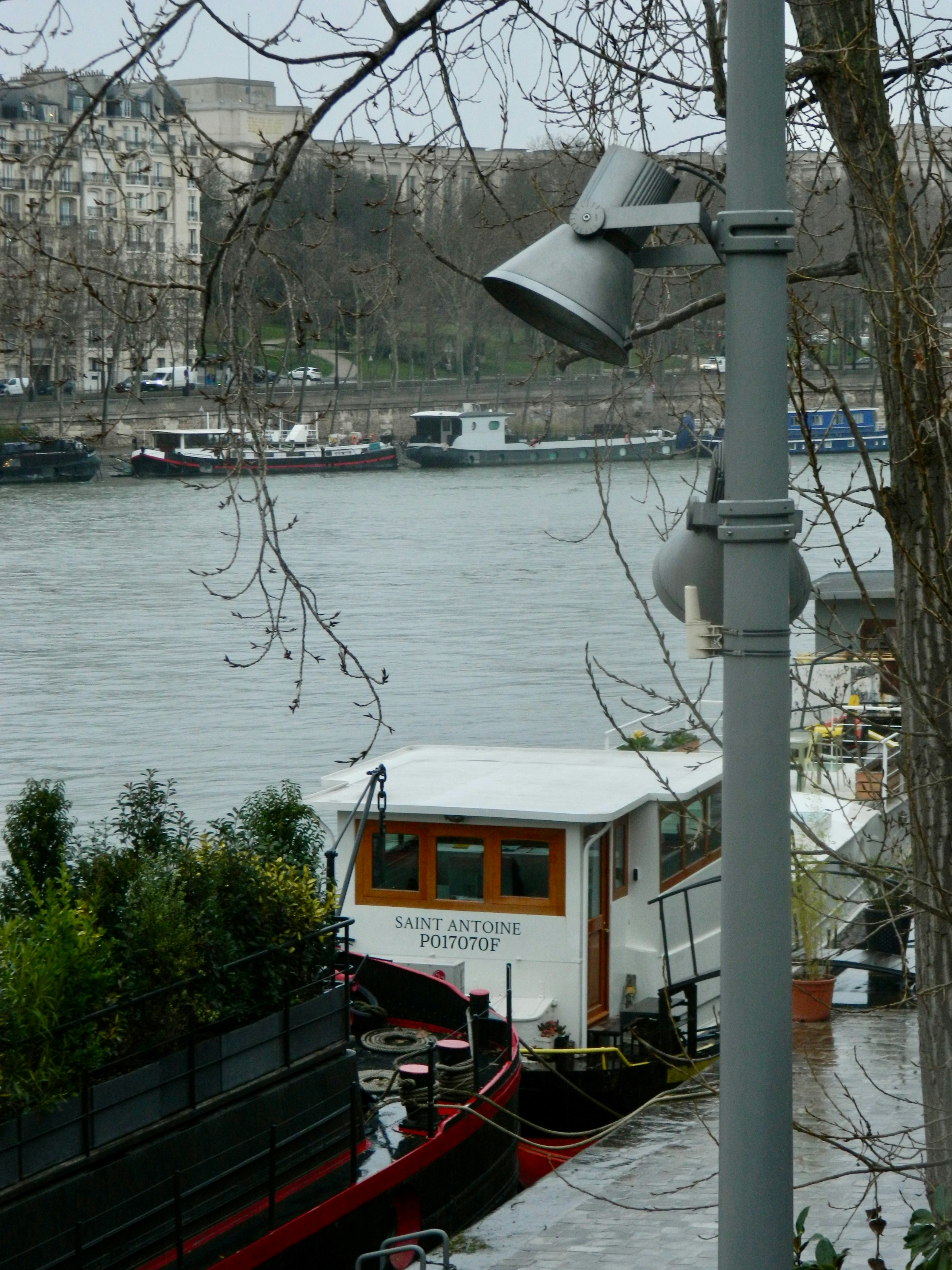 Una casa flotante atracada en un río con edificios de la ciudad detrás.