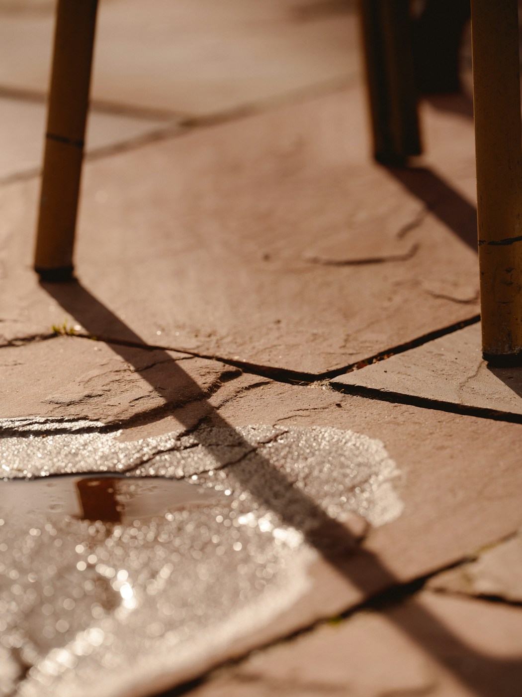 Rainwater pooling on a stone patio surface beside outdoor chair legs