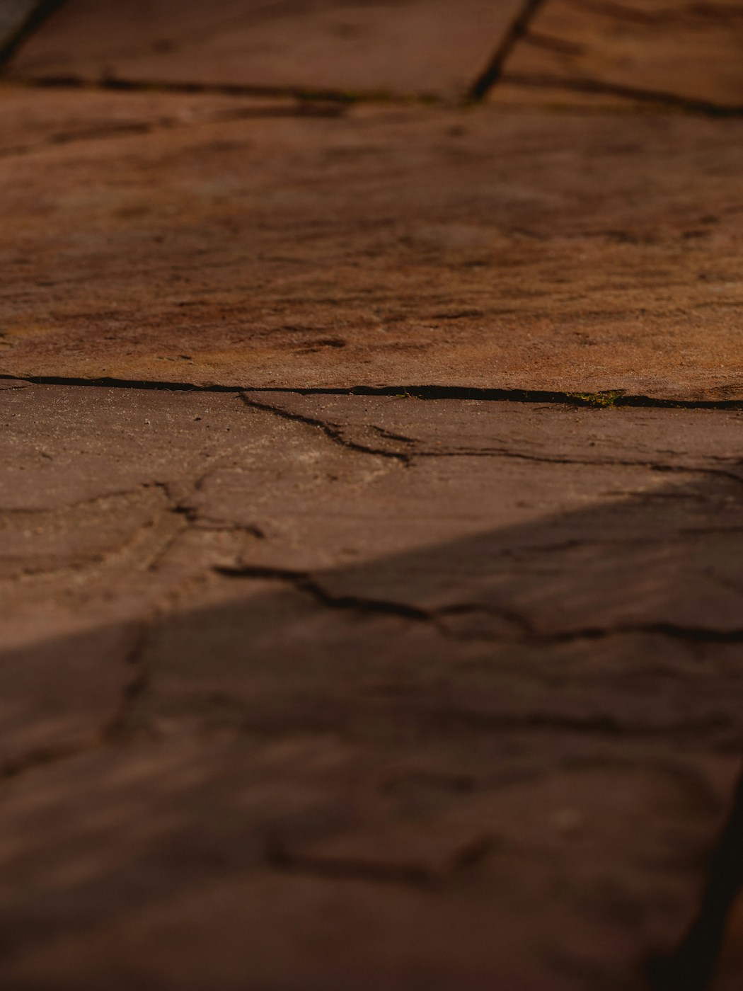 Close view of layered stone paving with warm brown tones and soft shadows across the surface