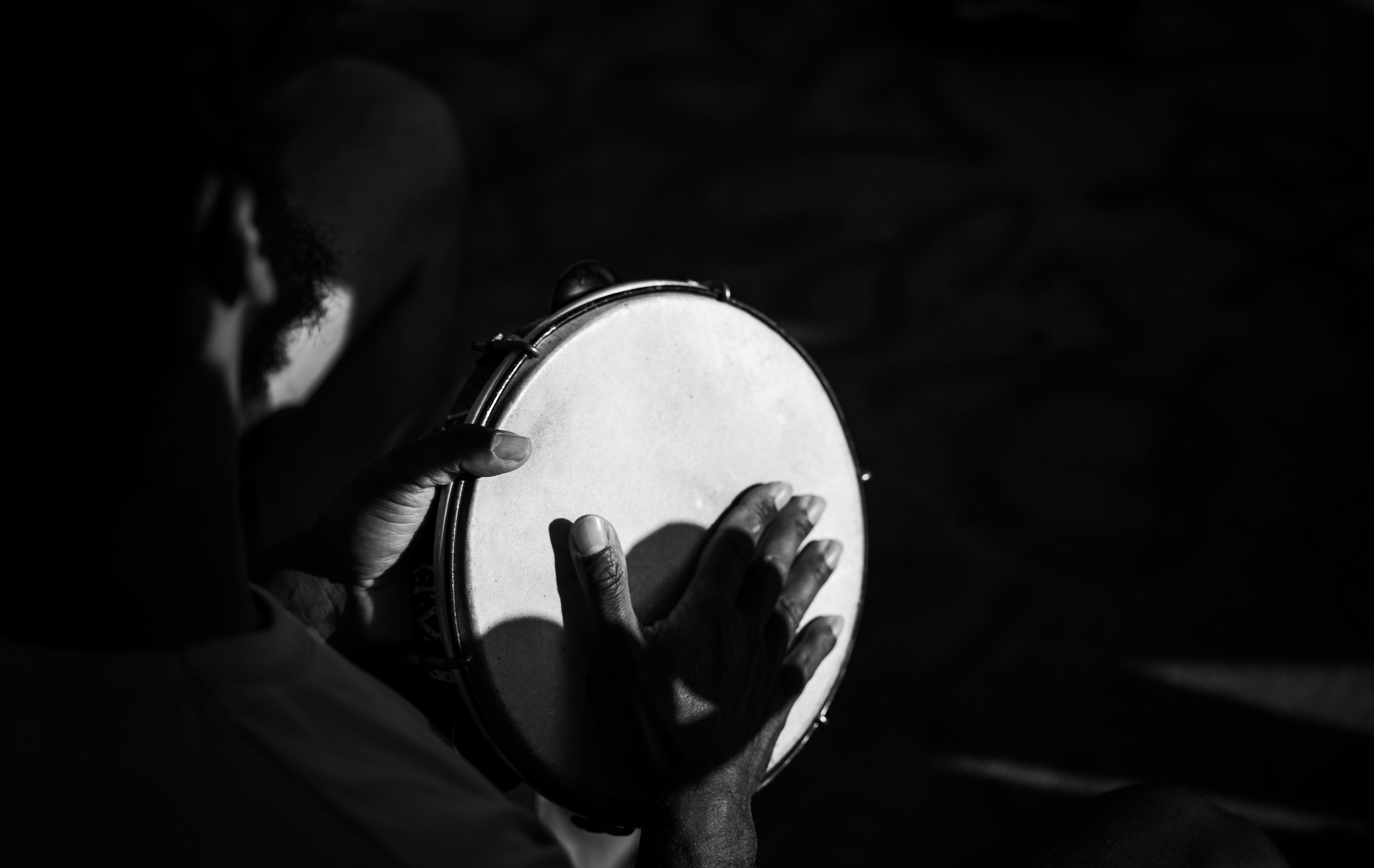 Musician playing a tambourine in dim light.