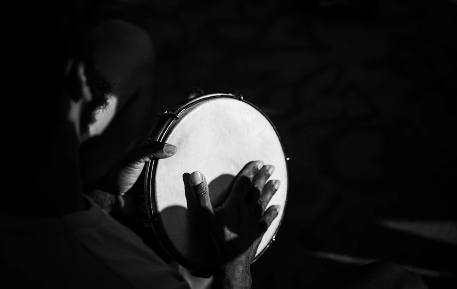 A musician playing the pandeiro in low light