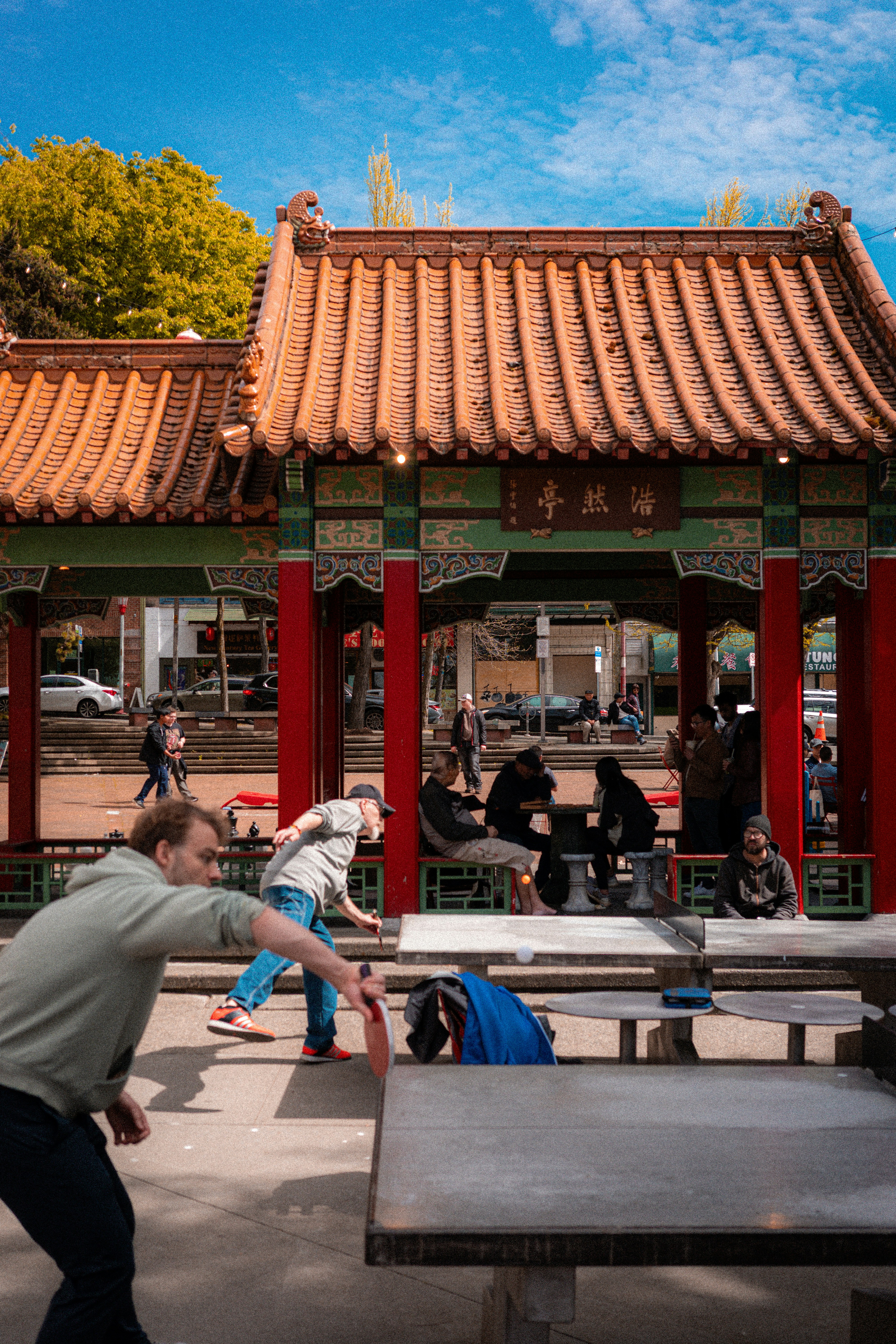 Pessoas jogando pingue-pongue perto de um pavilhão chinês