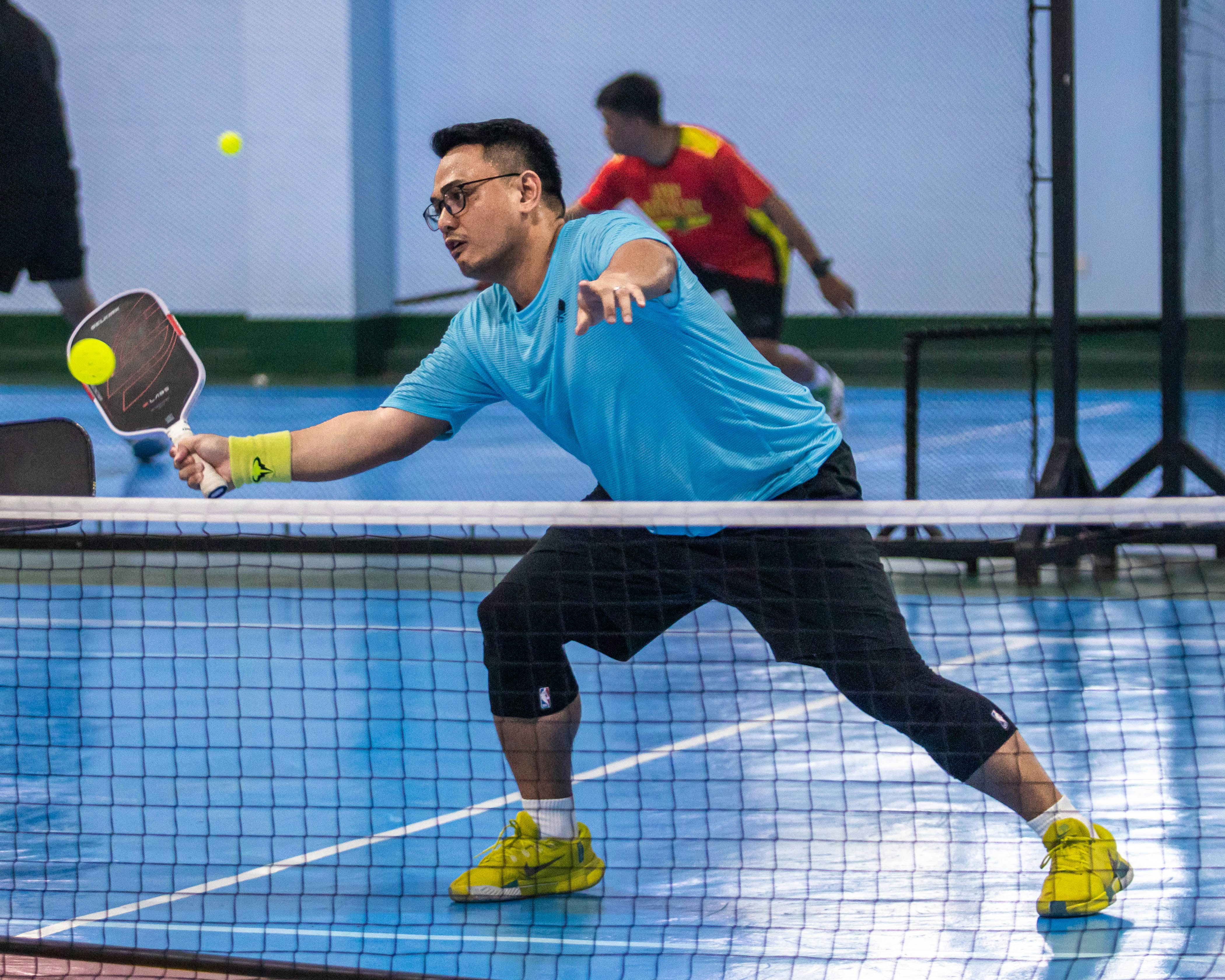 Mann, der Pickleball auf einem blauen Platz spielt.