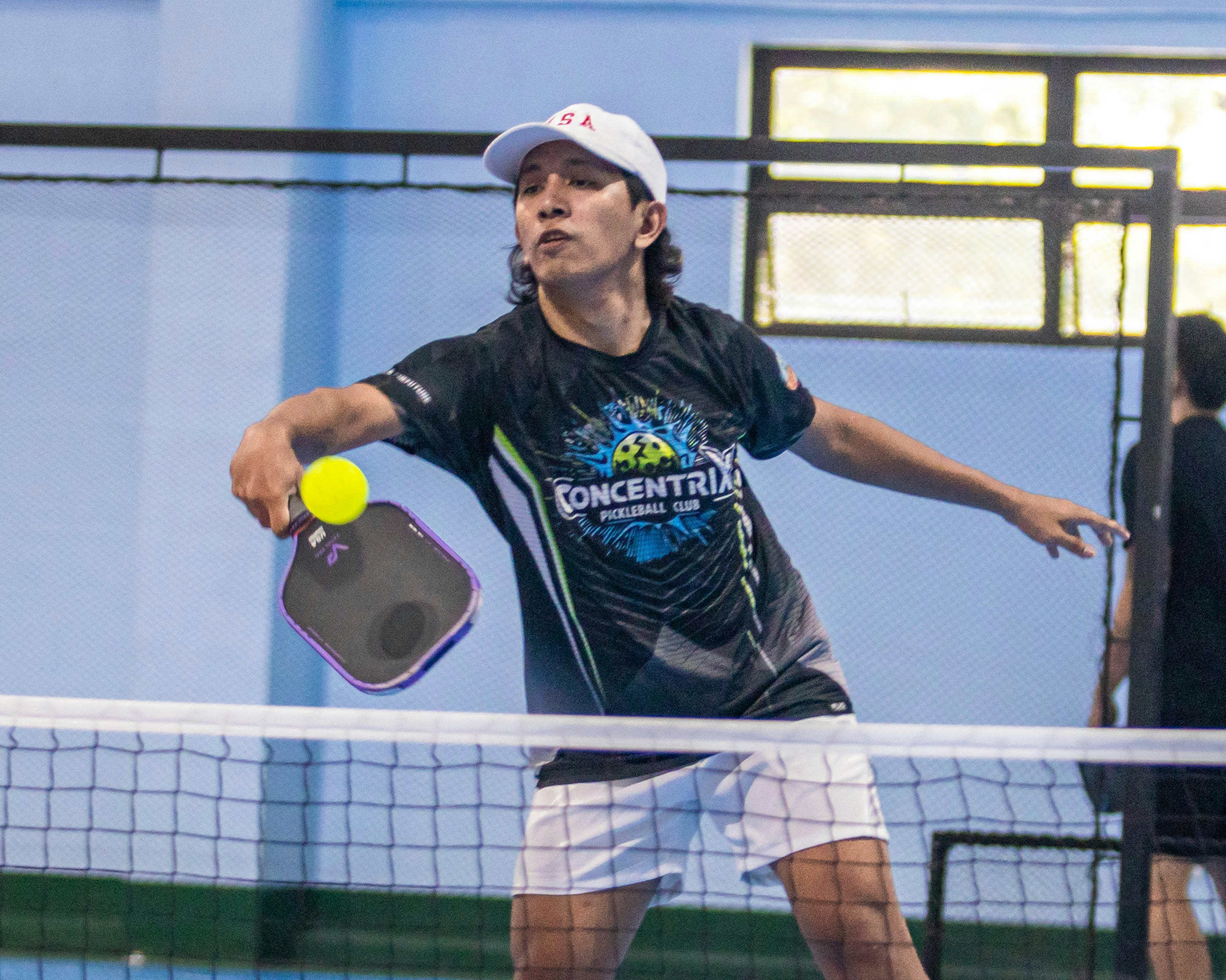 A man playing pickleball on an indoor court.