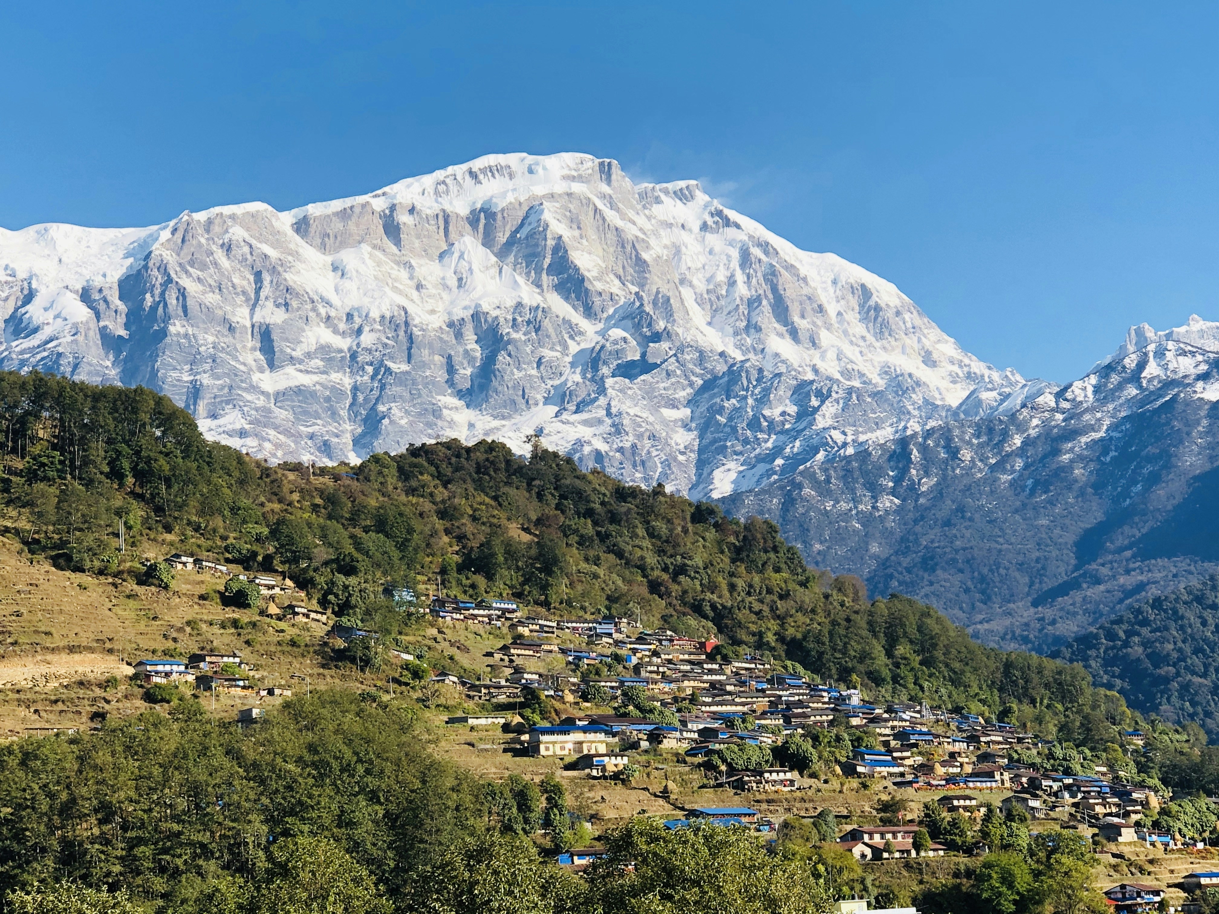 A village nestled at the base of a snow-capped mountain
