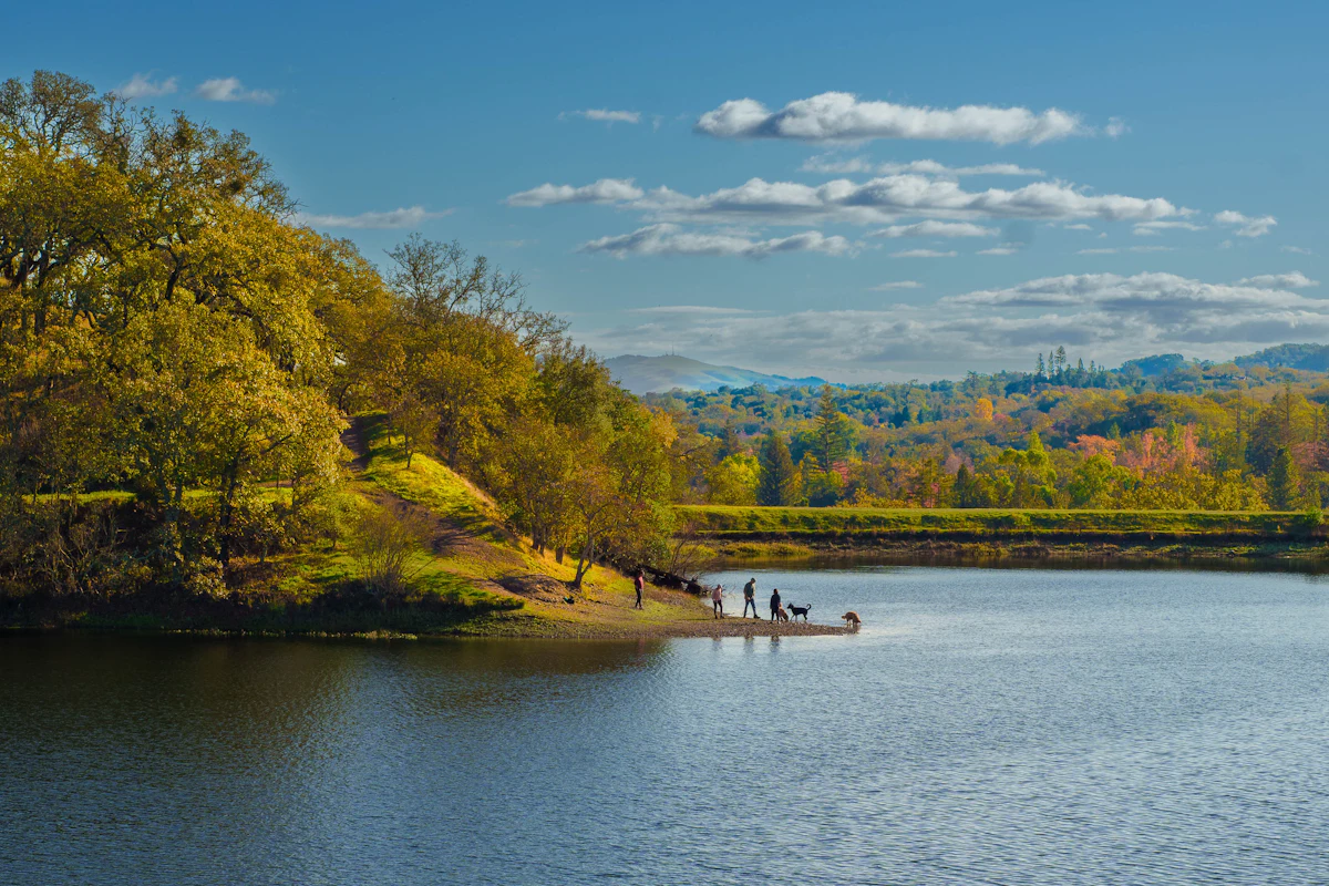 A calm lake near the town of Sonoma, with autumn trees on a point and people fishing from the shore