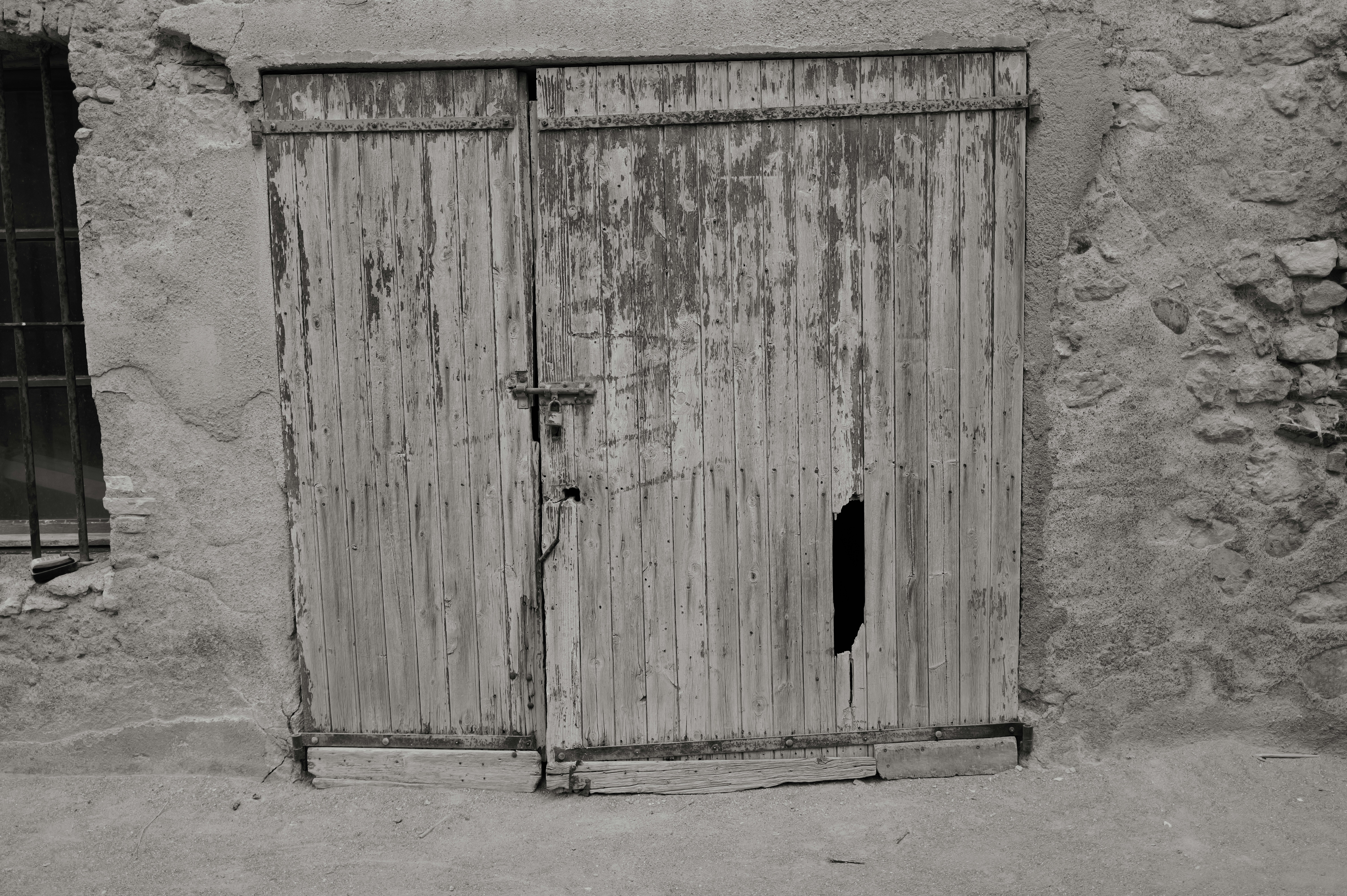 Pintu ganda kayu tua lapuk dengan lubang.