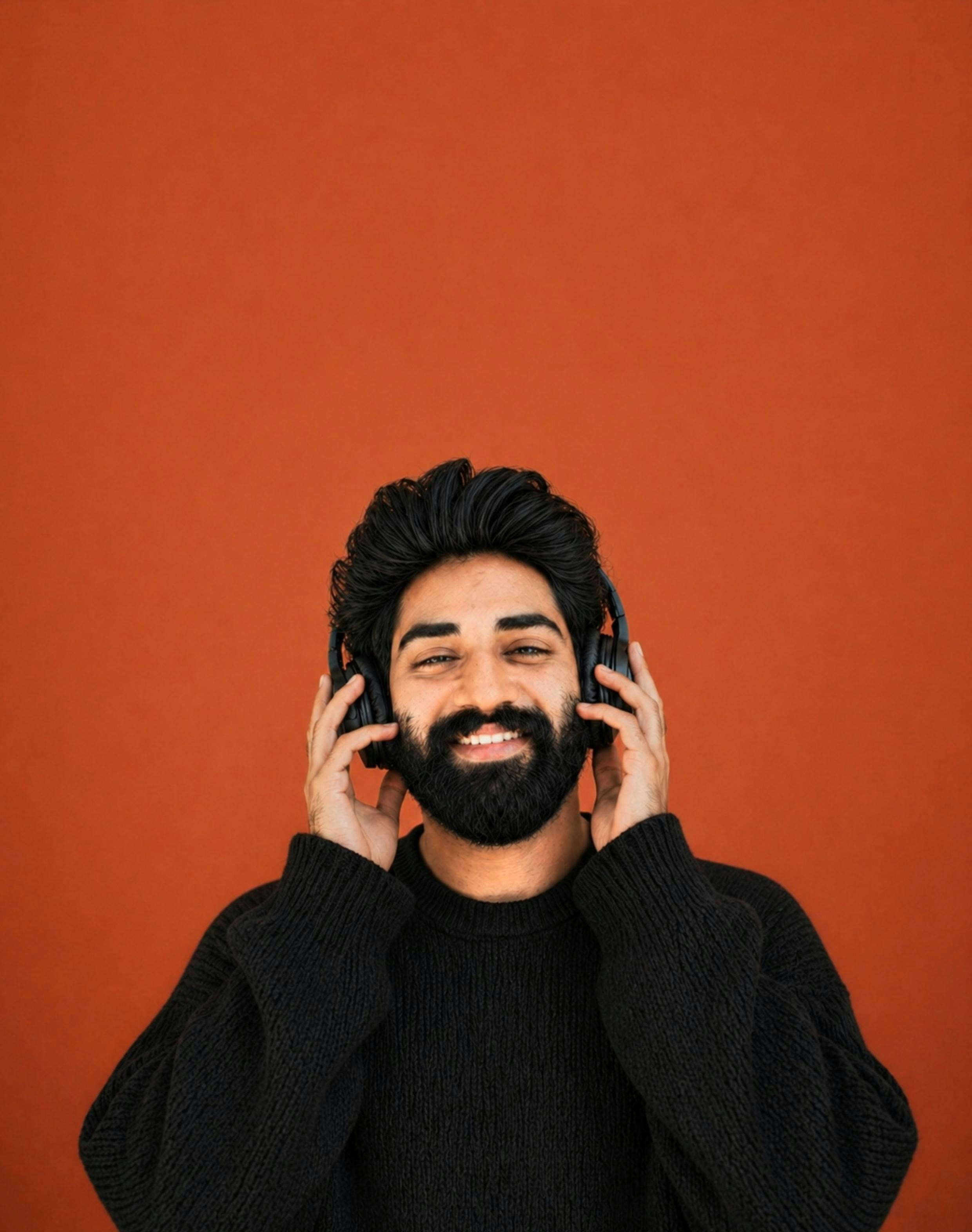 Man with headphones smiles against orange background