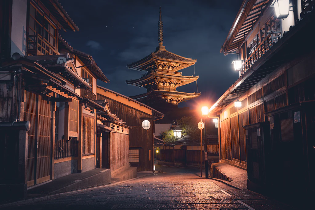 An empty Kyoto lane lined with dark wooden townhouses, a lit pagoda at the end of it