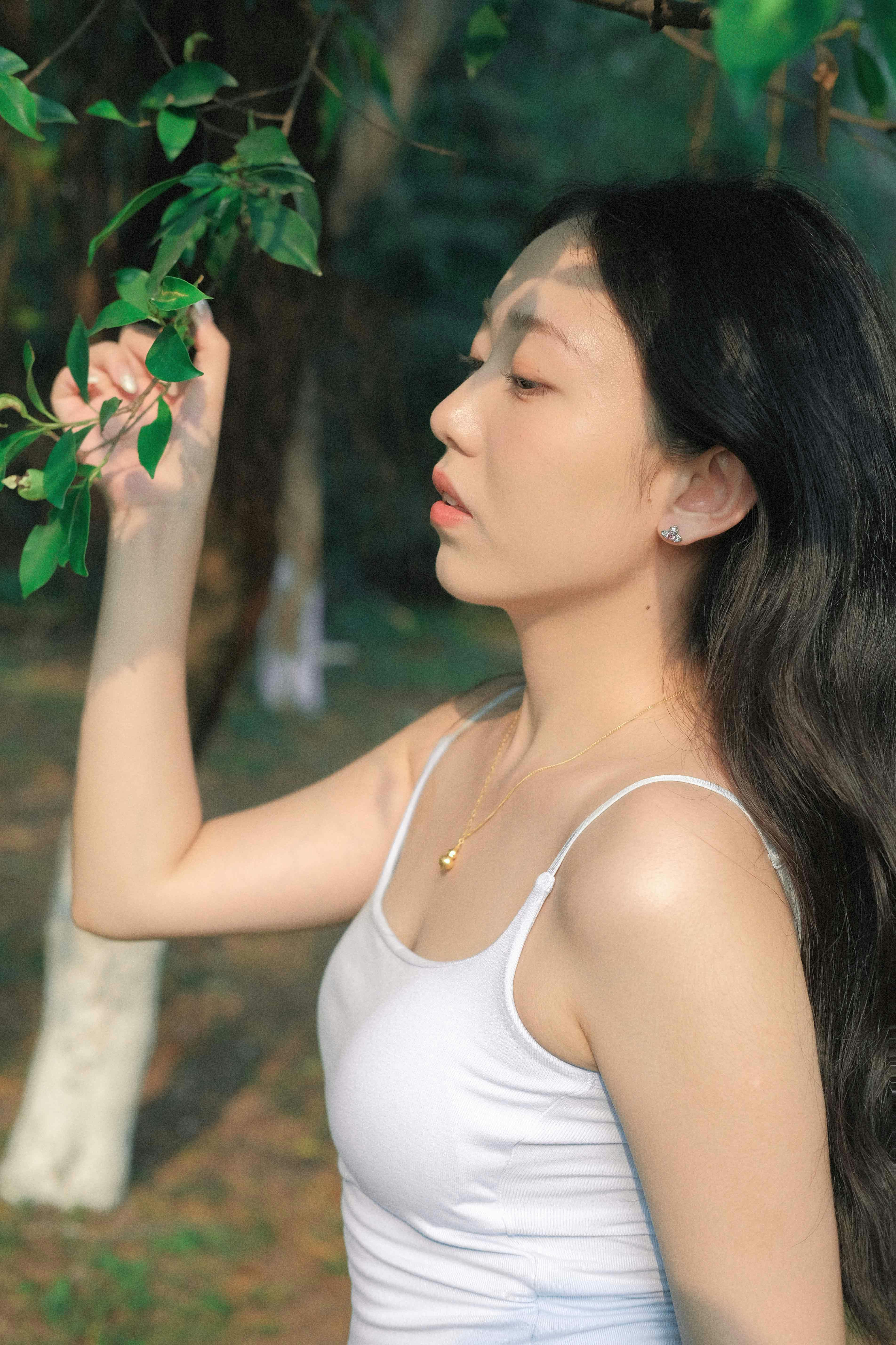 Joven con camiseta blanca tocando hojas al aire libre