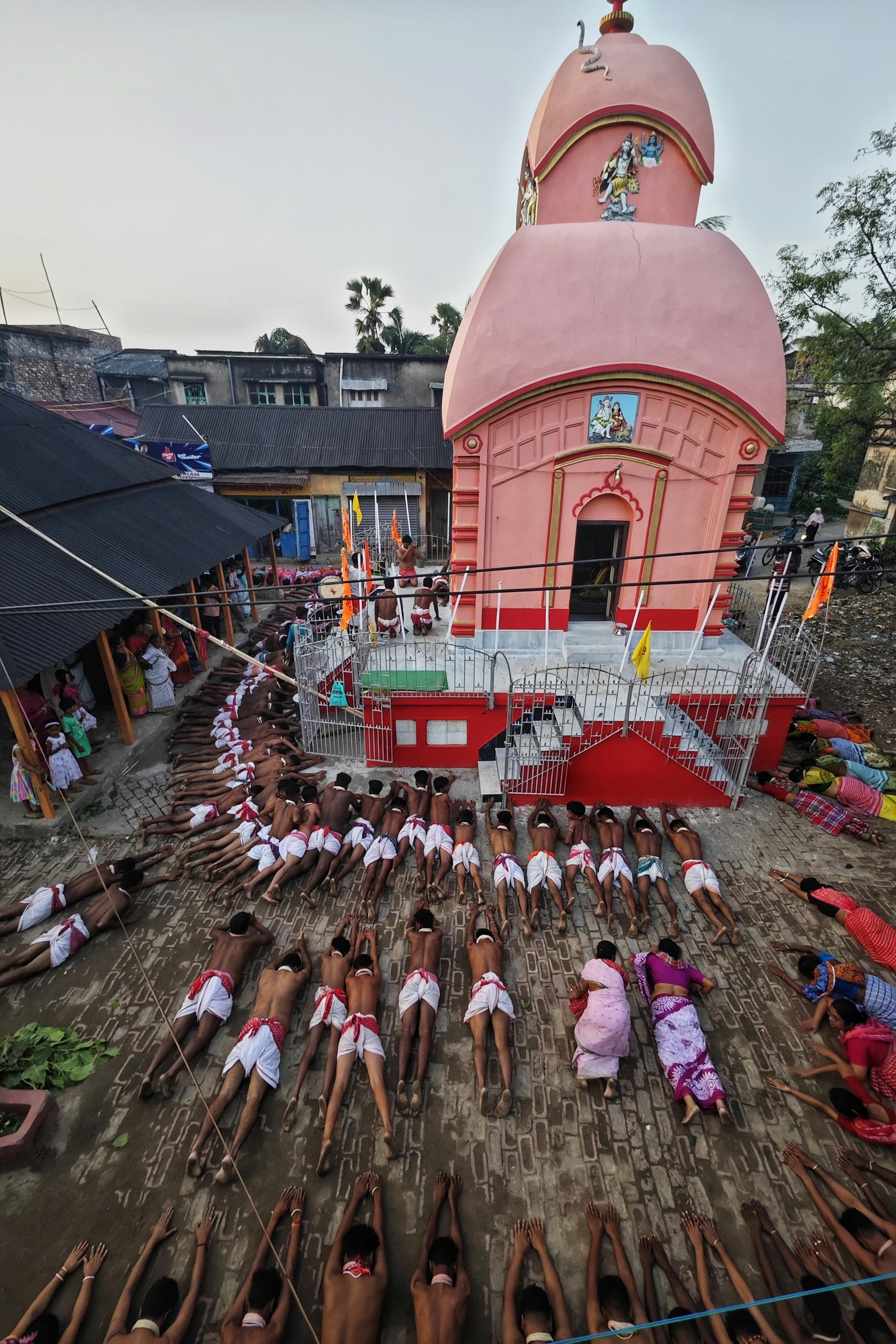 Los hombres yacen en filas frente a un templo rosa