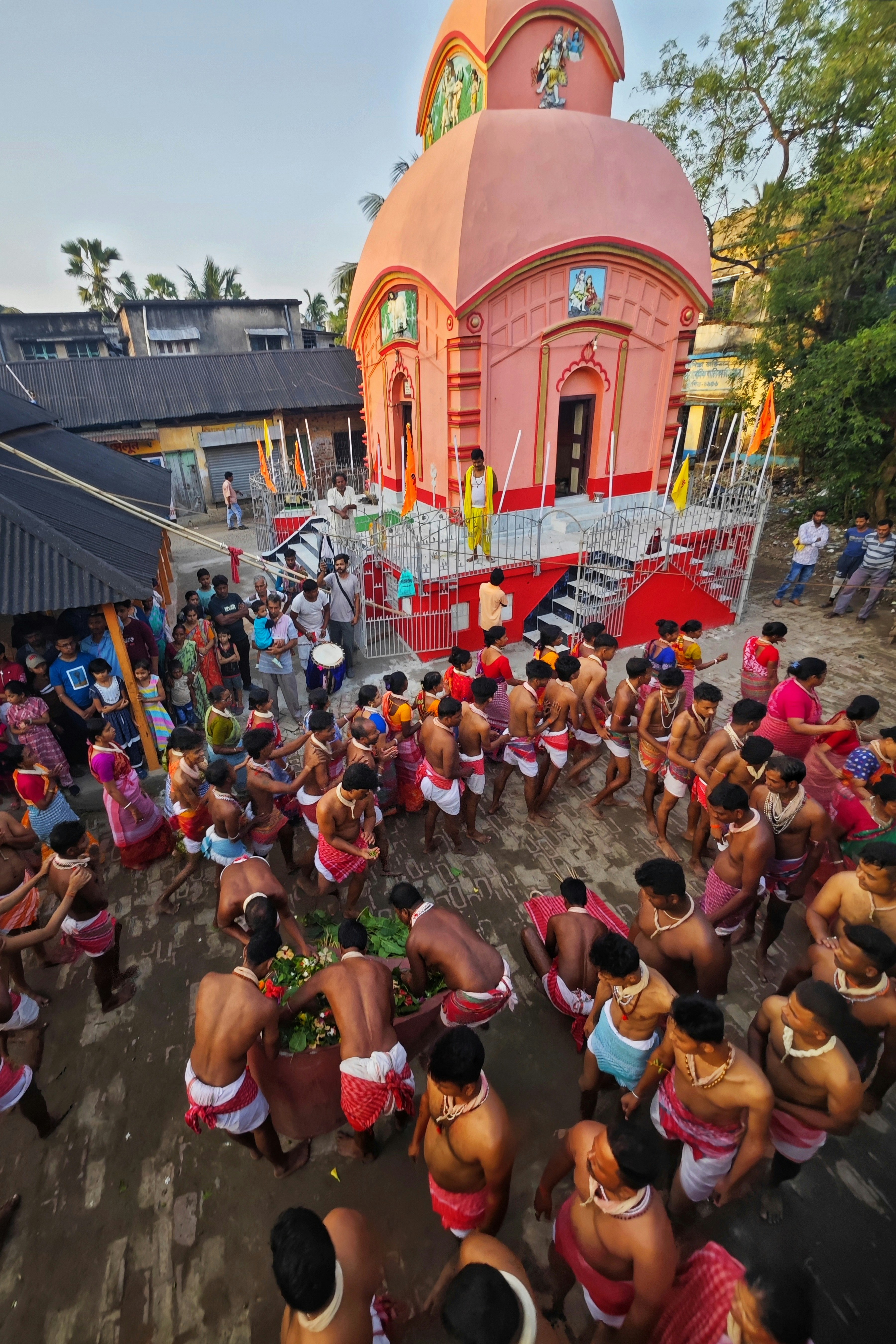 La gente se reúne para una ceremonia religiosa en un templo rosa.