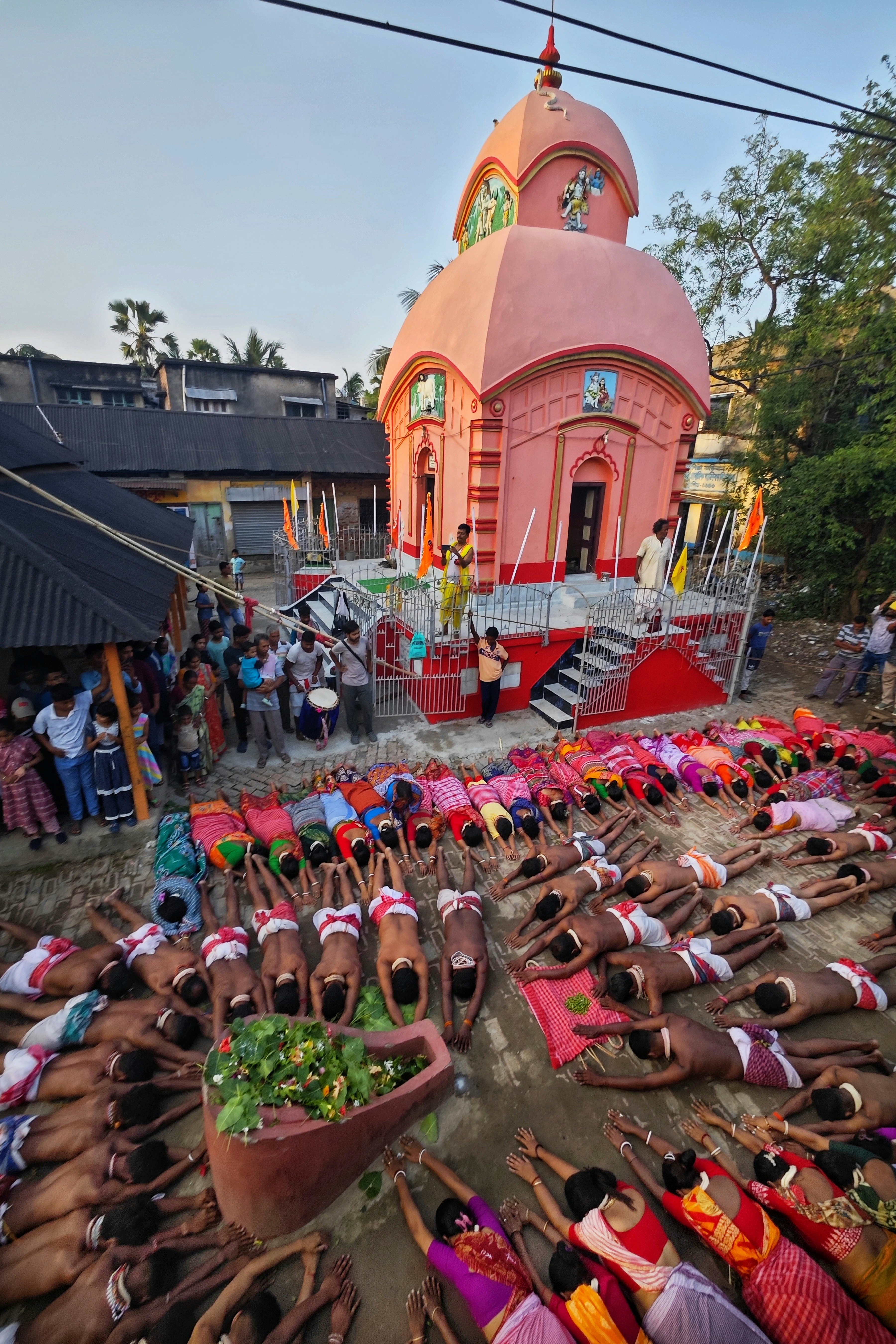 La gente se postra ante un templo rosa durante una ceremonia religiosa.