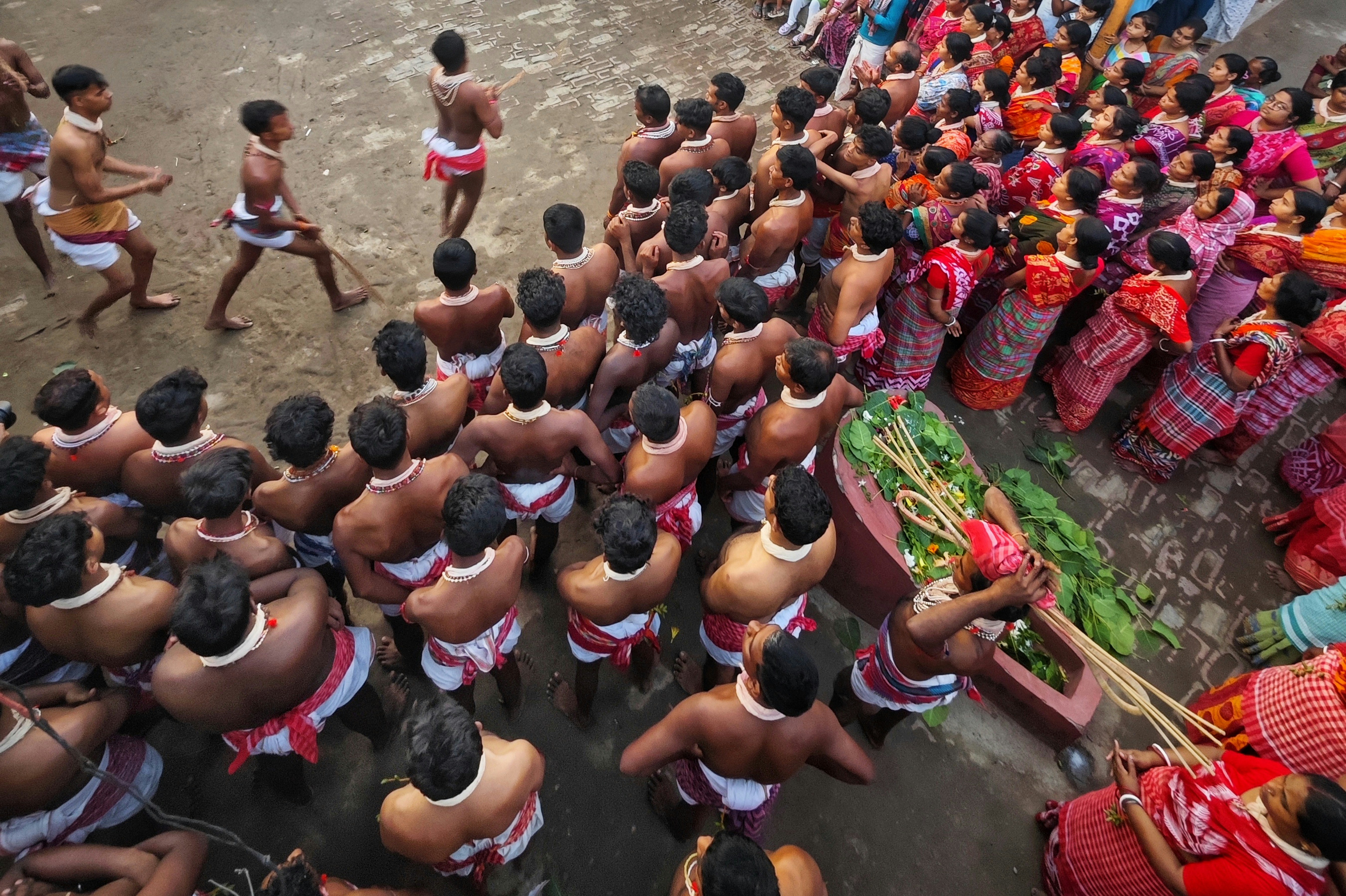 La multitud observa a hombres con atuendos tradicionales durante un festival.